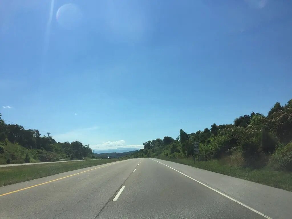 Dálnice s výhledem na vzdálené hory, modrá obloha, značka Speed Limit 65