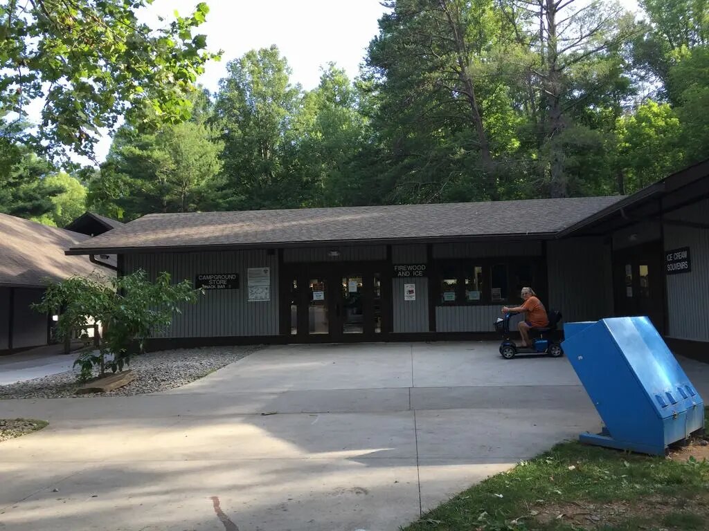 Budova Campground Store, nápisy Firewood and Ice, Ice Cream Souvenirs, muž na skútru.