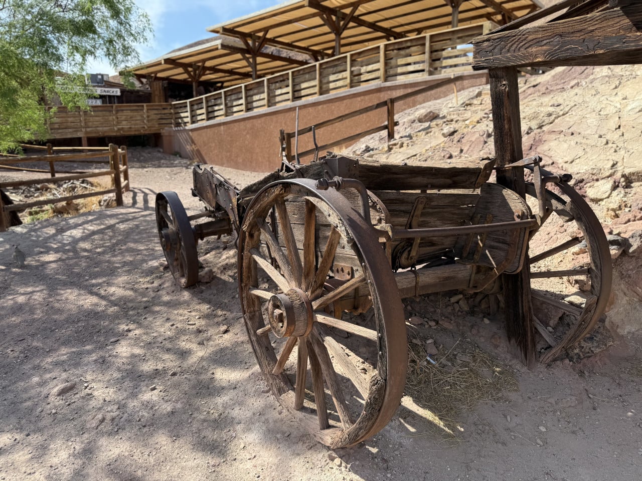 Dřevěný povoz u cesty v Calico Ghost Town, pouštní svah a přístřešek nahoře.