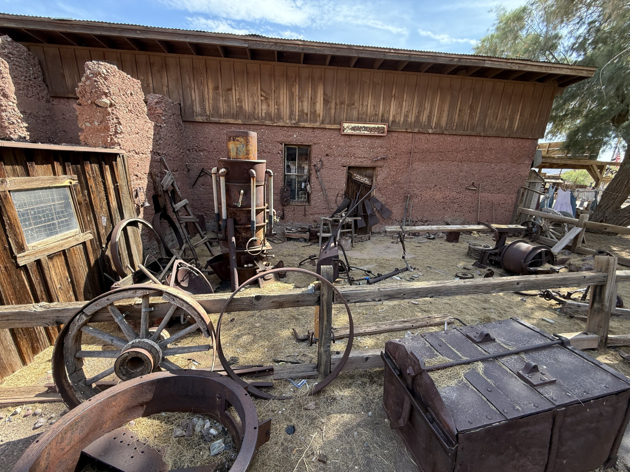 Expozice starého dílenského dvora s rezavými stroji a dřevěnou budovou.