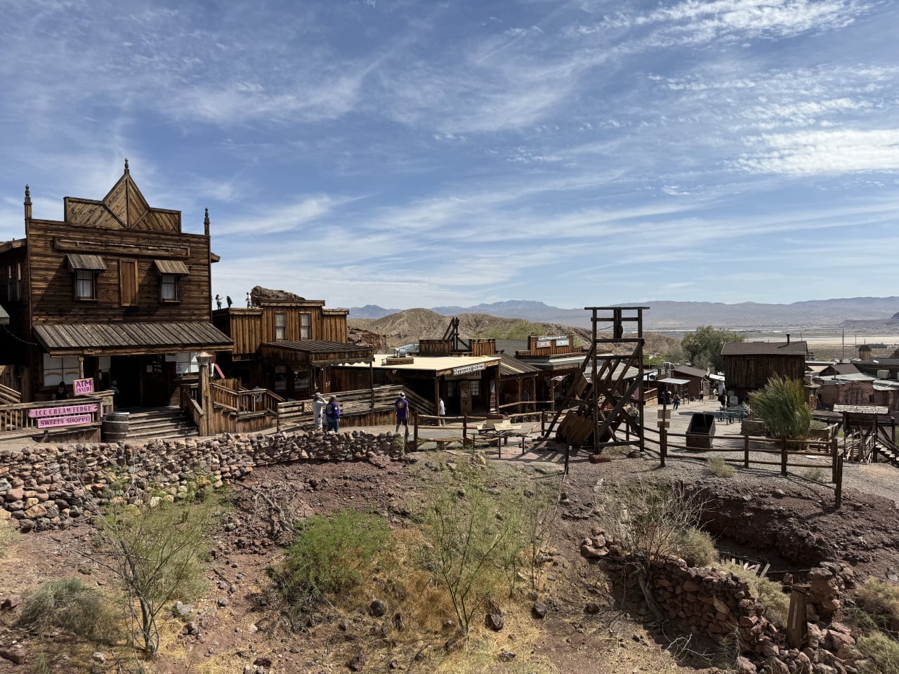 Dřevěné budovy v Calico Ghost Town v poušti, s výhledem na hory a oblohu.