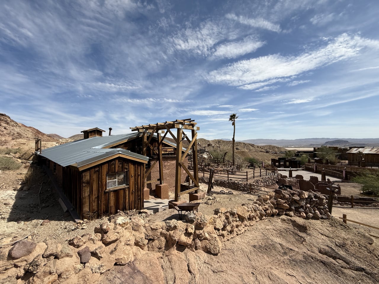 Dřevěné budovy Calico Ghost Town v pouštní krajině pod modrou oblohou