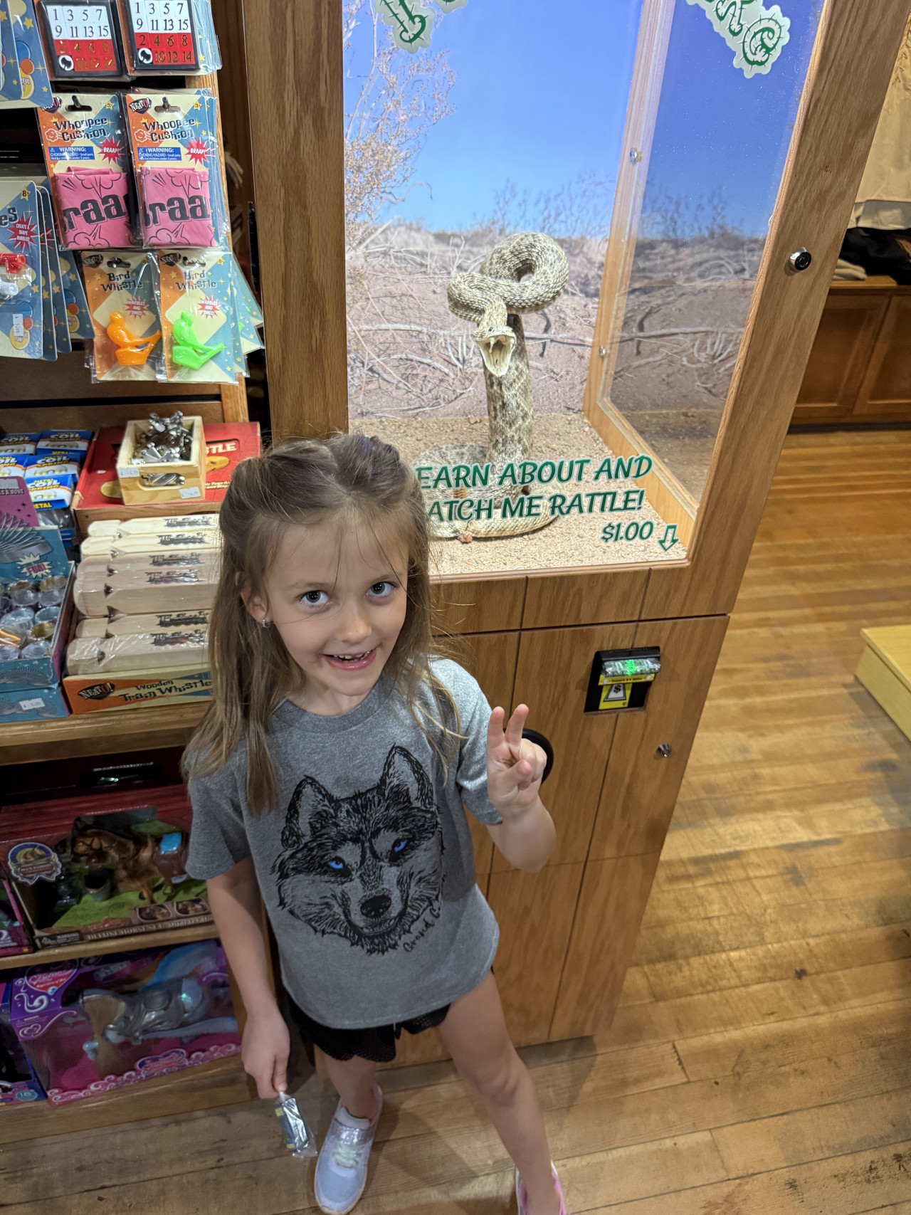 Děvčátko v obchodě s dárky před vystavenou chřestýší a suvenýry.