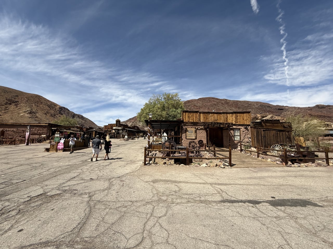 Prázdné westernové městečko v poušti s dřevěnými budovami a návštěvníky.