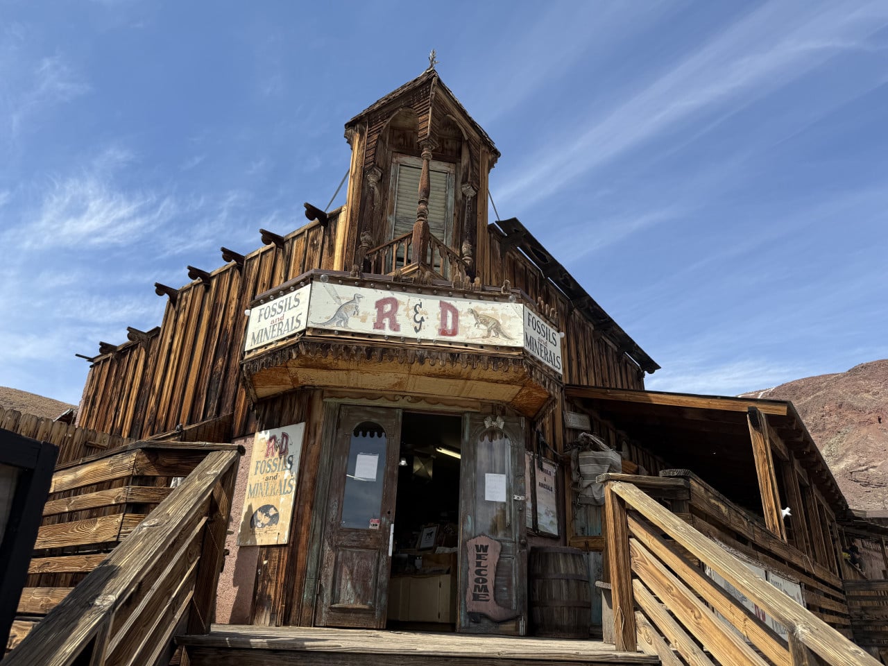 Dřevěný obchod v Calico Ghost Town s nápisem Fossils and Minerals, pod modrou oblohou.