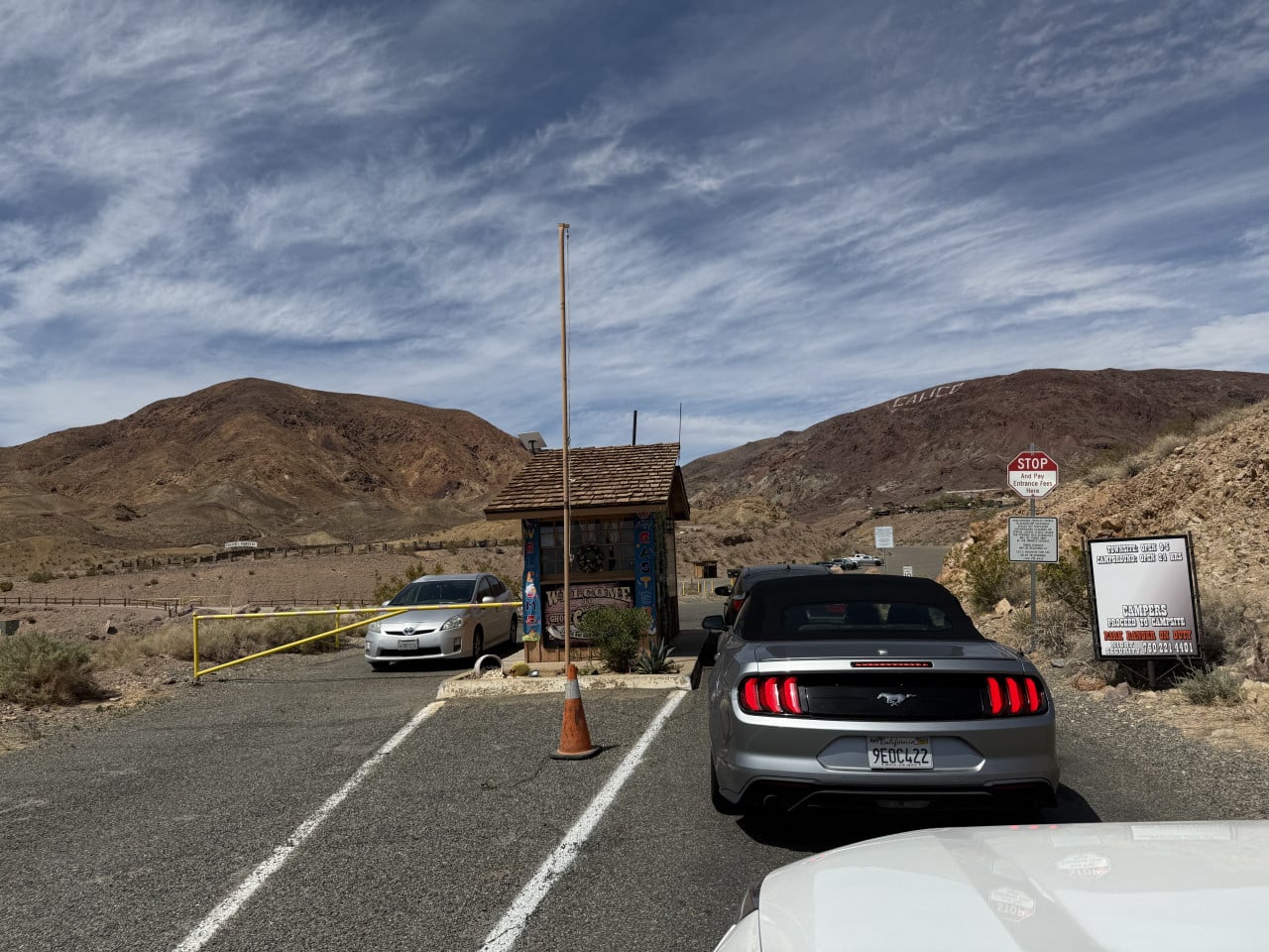 Vjezd do Calico Ghost Town v poušti, auta a stop značka u malého domku