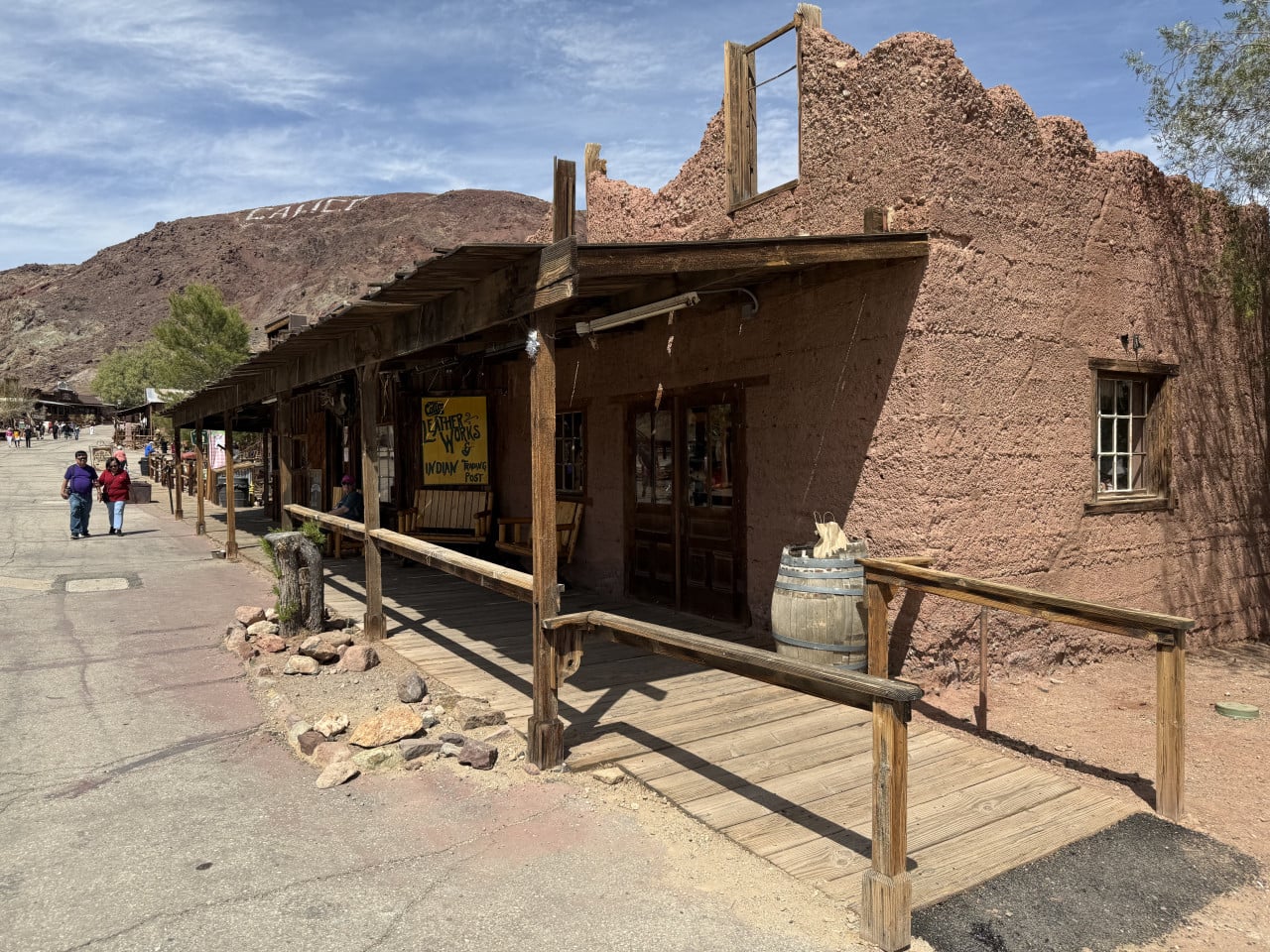 Dřevěná budova v Calico Ghost Town s verandou a pouštním kopcem v pozadí