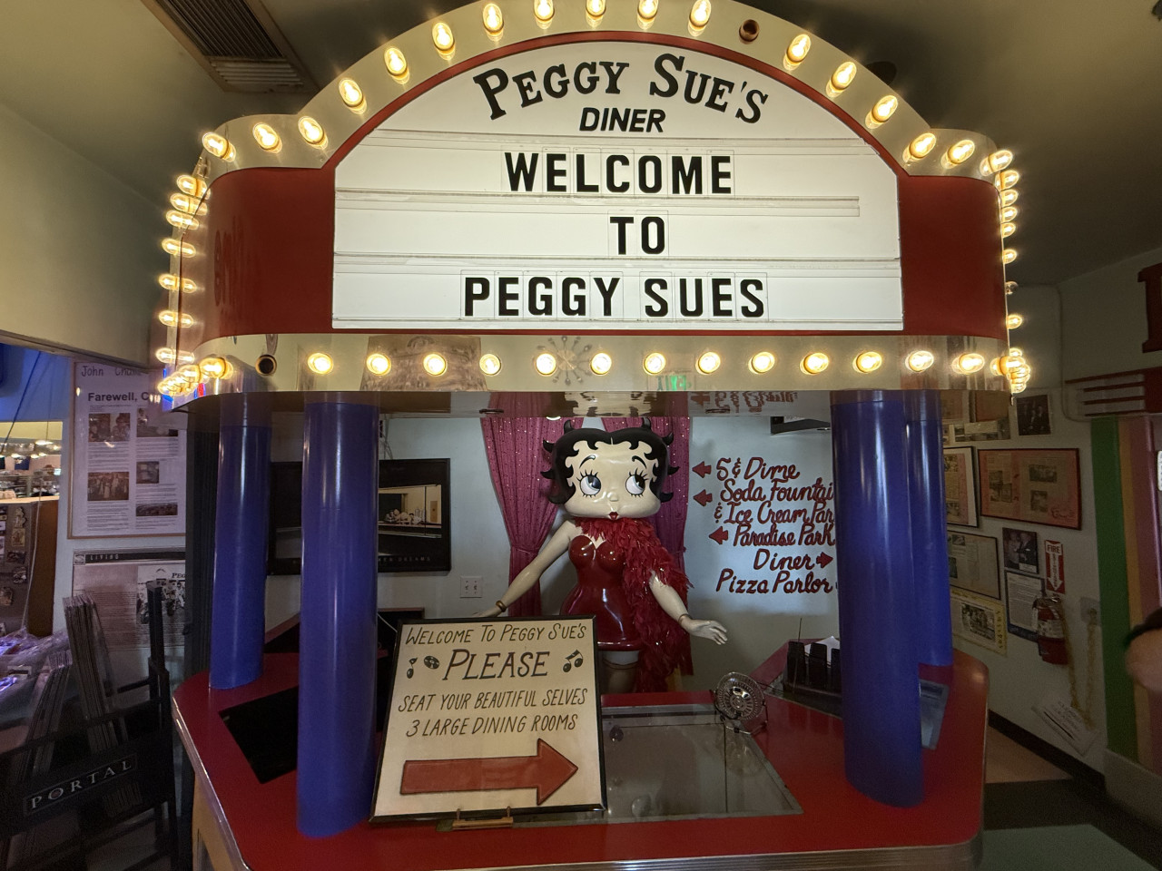 Svítící retro vchod do Peggy Sue's Diner s Betty Boop a nápisem Welcome to Peggy Sues.