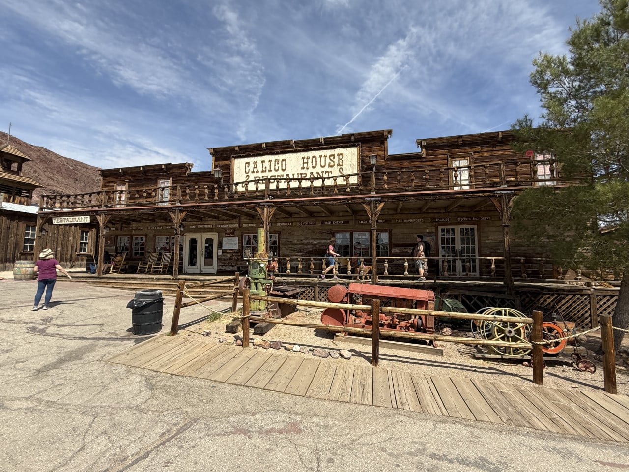 Dřevěná budova Calico House Restaurant v pouštním ghost townu, lidé na verandě.