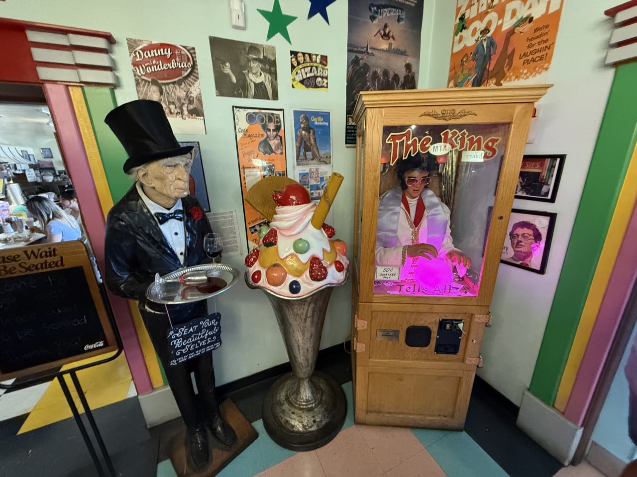 Barevné retro figuríny a automat The King s nápisem Tells All v interiéru.