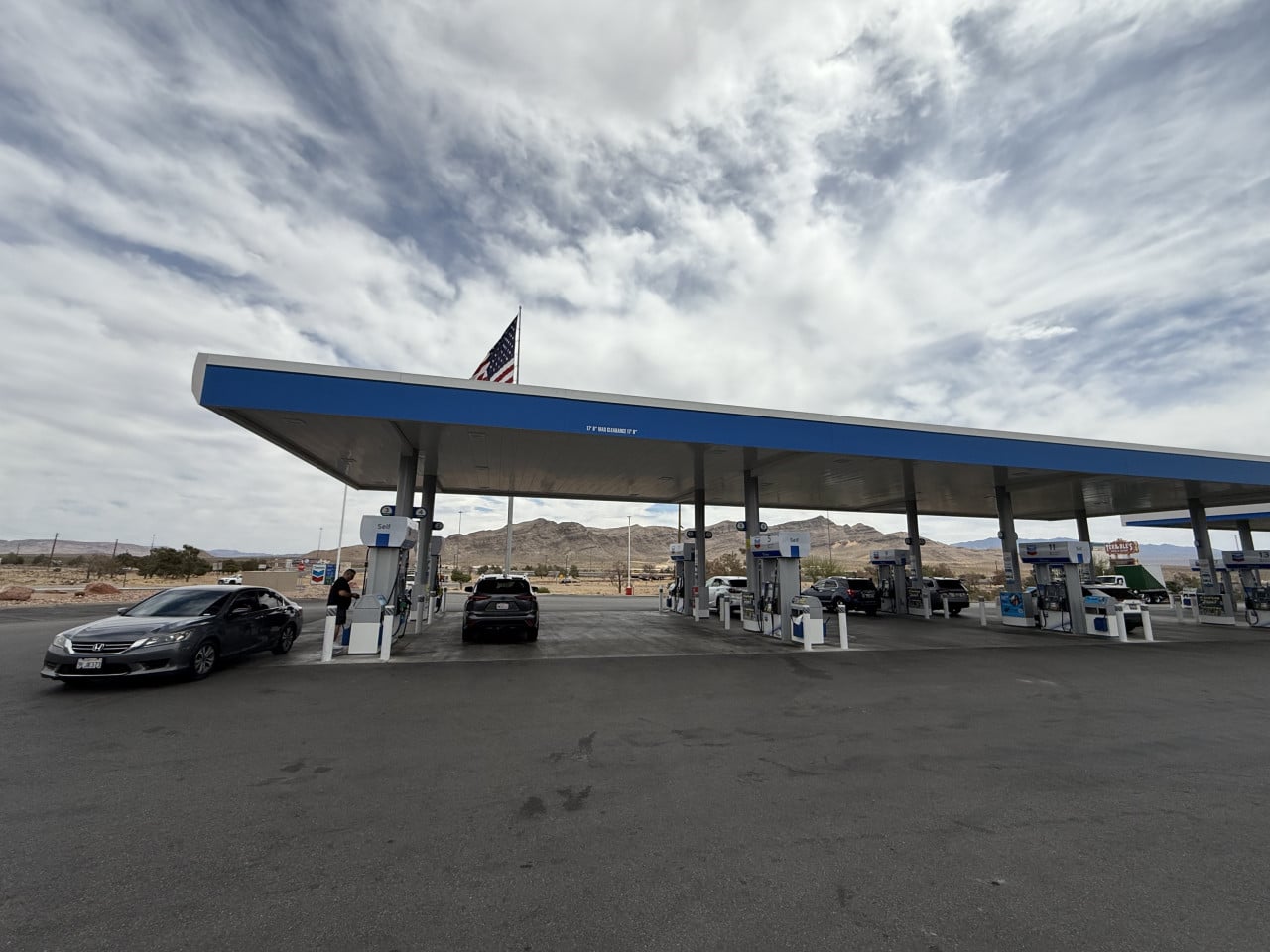 Chevron čerpací stanice v poušti s auty a americkou vlajkou nad střechou