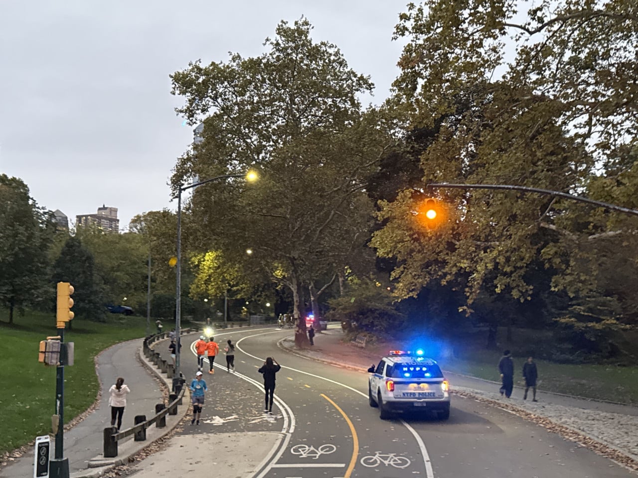 Večerní silnice v Central Parku s policií NYPD a chodci mezi stromy