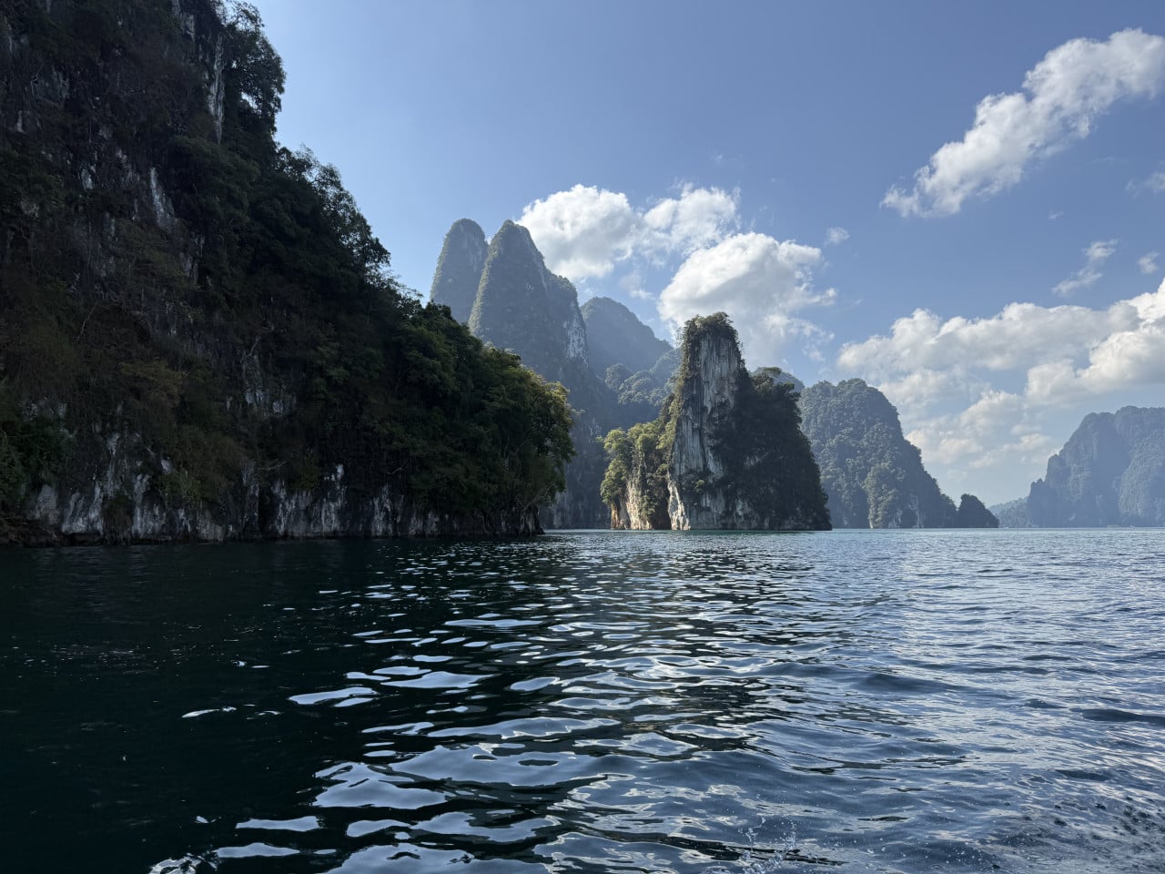 Smaragdové jezero s vápencovými skalami a džunglí pod modrou oblohou s mraky