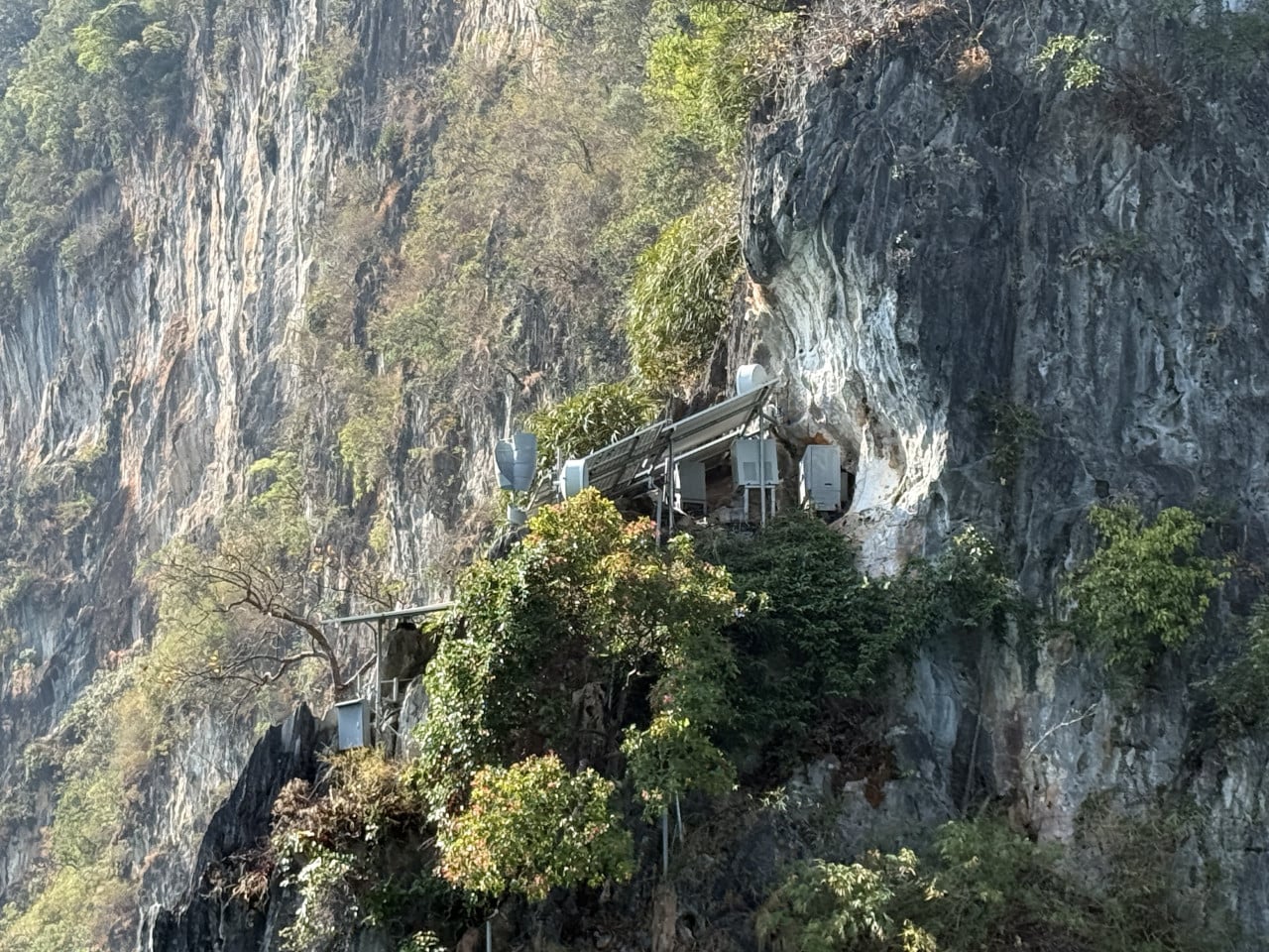 Ocelová konstrukce se satelitní anténou připevněná na strmé vápencové skále.