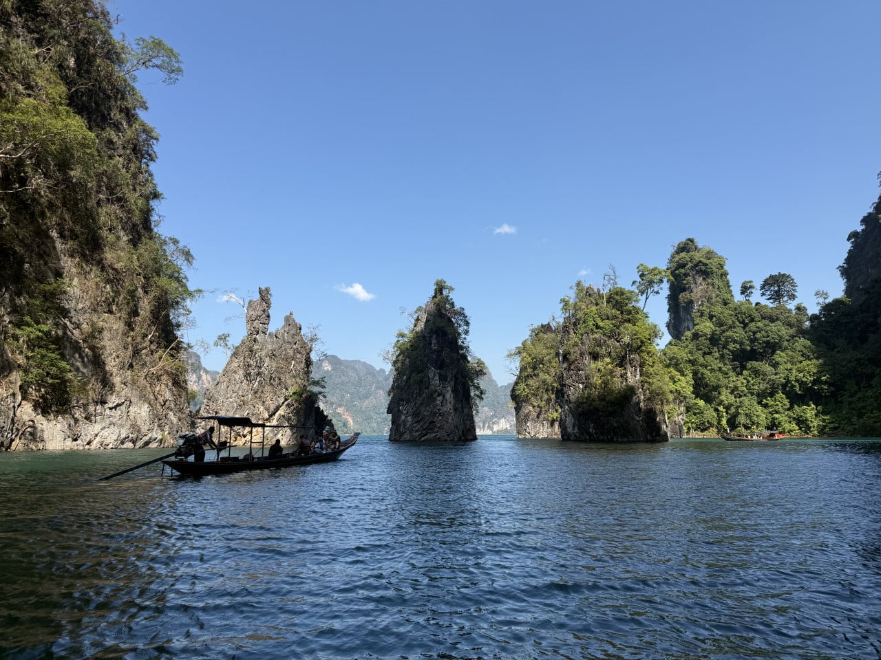 Loď s turisty na jezeře Cheow Lan mezi vápencovými skalami a džunglí