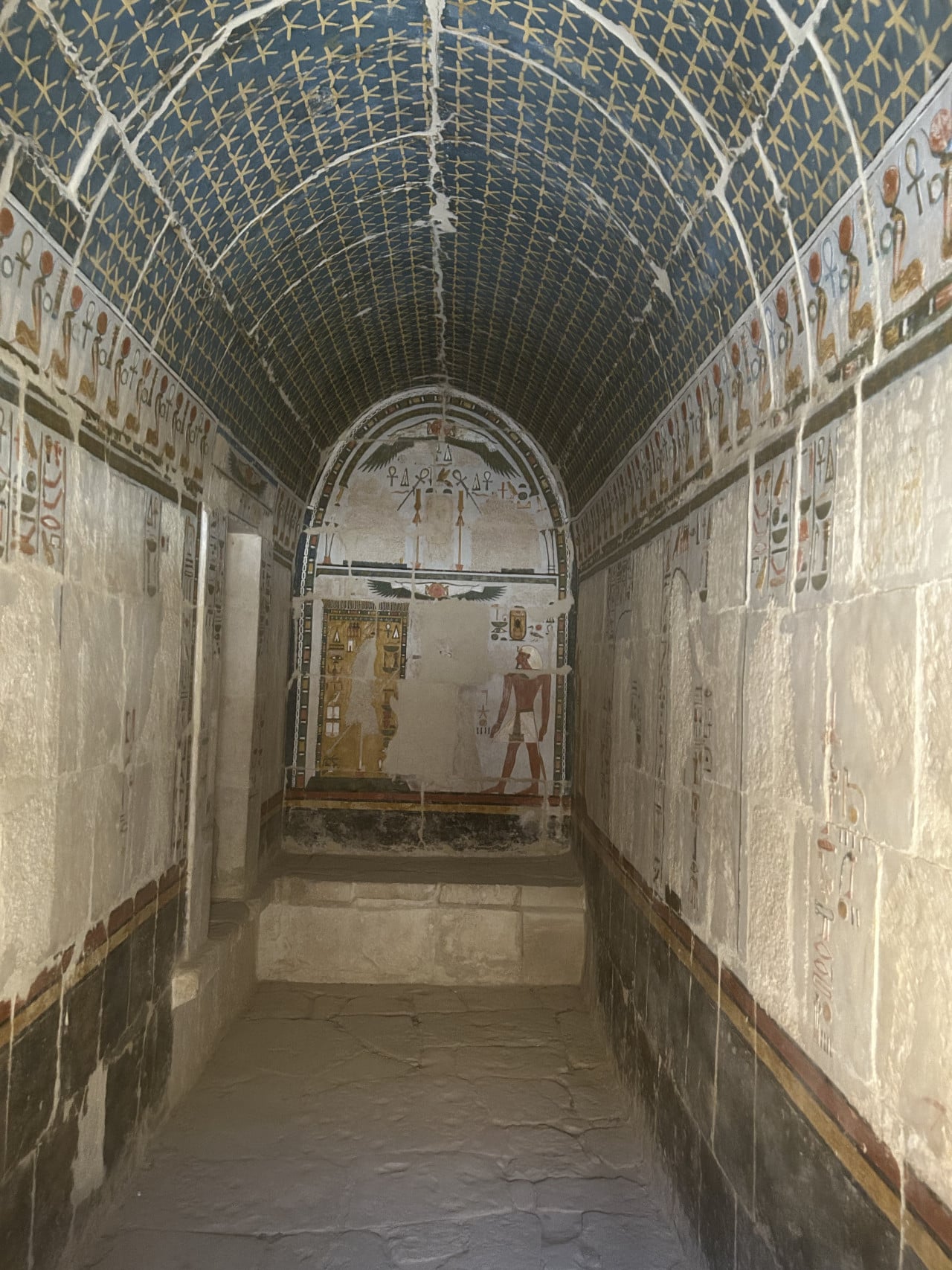 Úzká egyptská chodba s malovaným stropem a hieroglyfy na stěnách