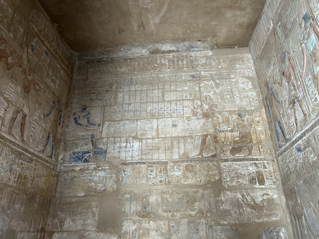 Ošlapané hieroglyfy a reliéfy v malované egyptské kamenné komoře