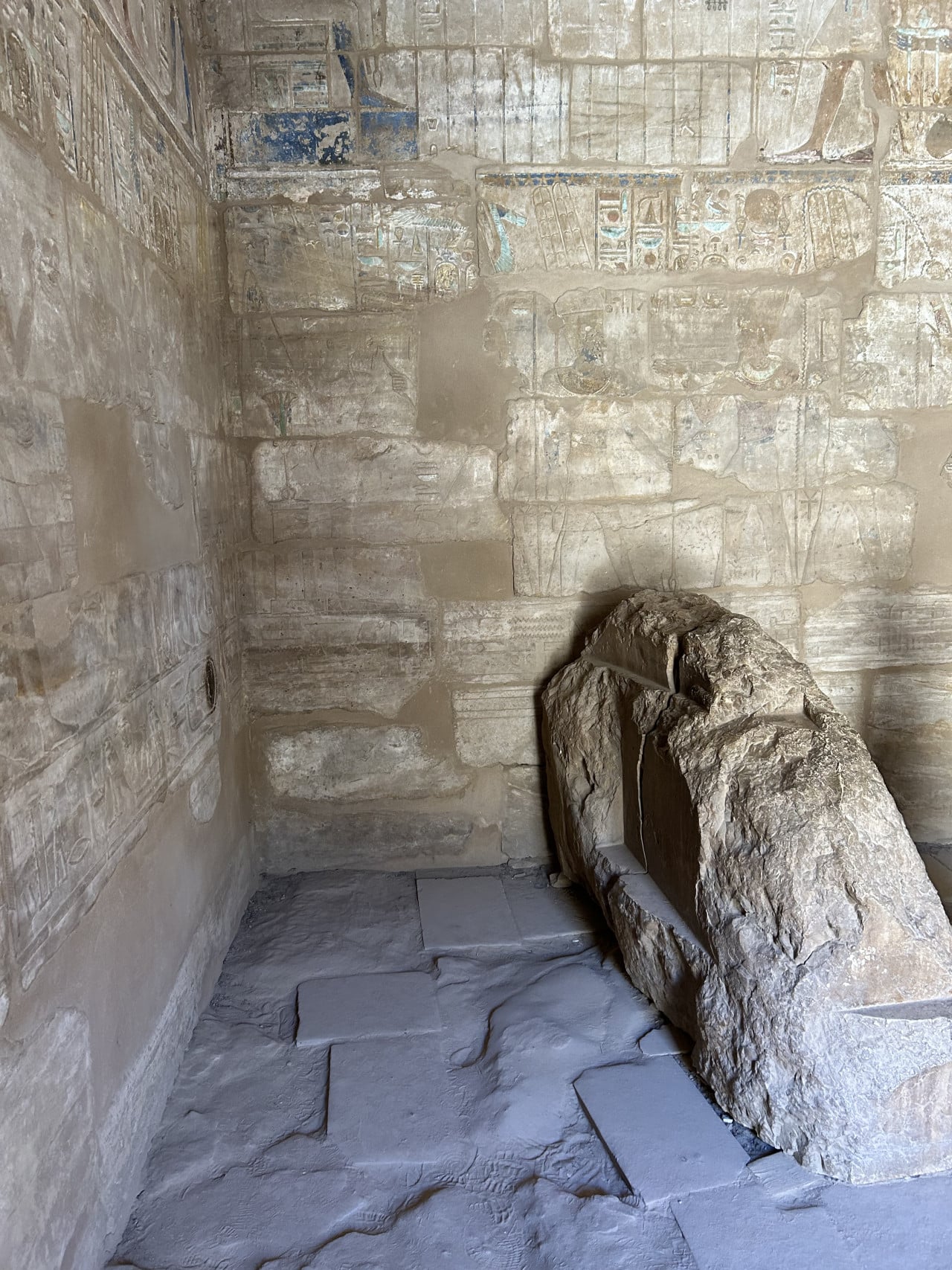 Kamenná rakev v egyptské chrámové místnosti s vybledlými hieroglyfy na stěnách.