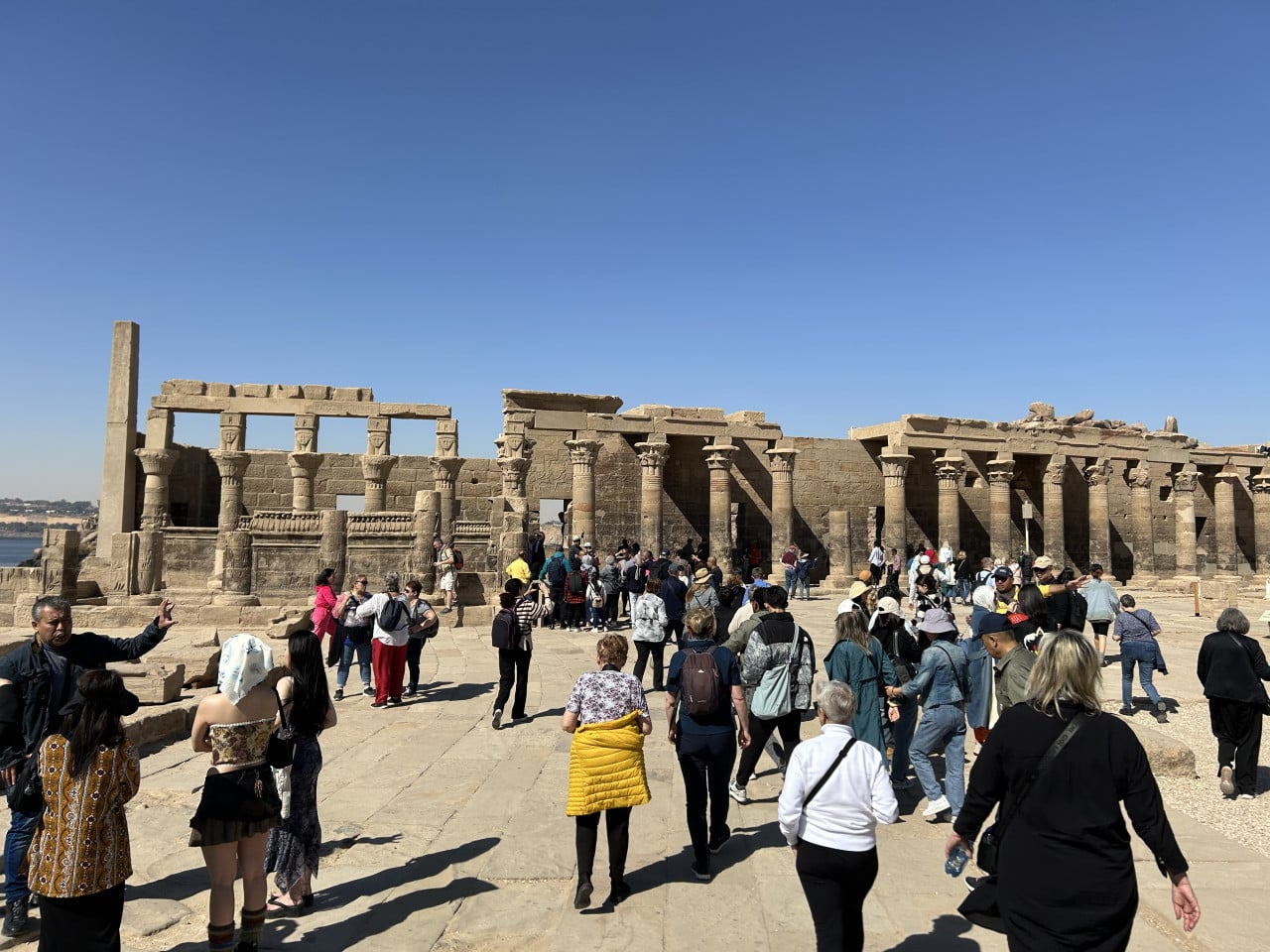 Turisté před chrámem Philae v Asuánu pod jasnou modrou oblohou