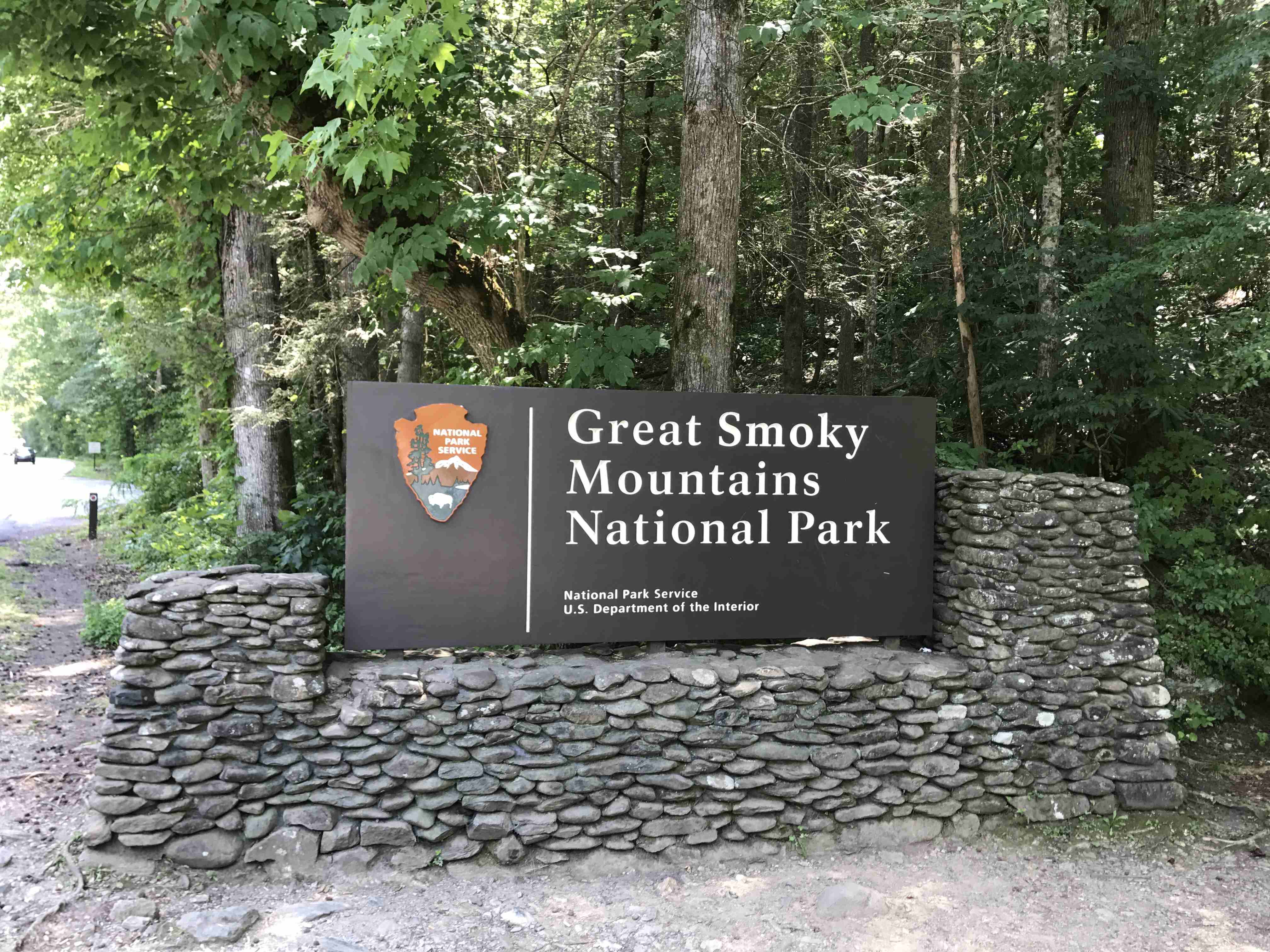 Vstupní cedule Great Smoky Mountains National Park na kamenné zídce v lese