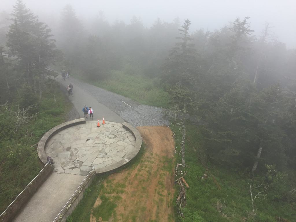 Kruhová vyhlídková plošina a turisté v husté mlze u lesa