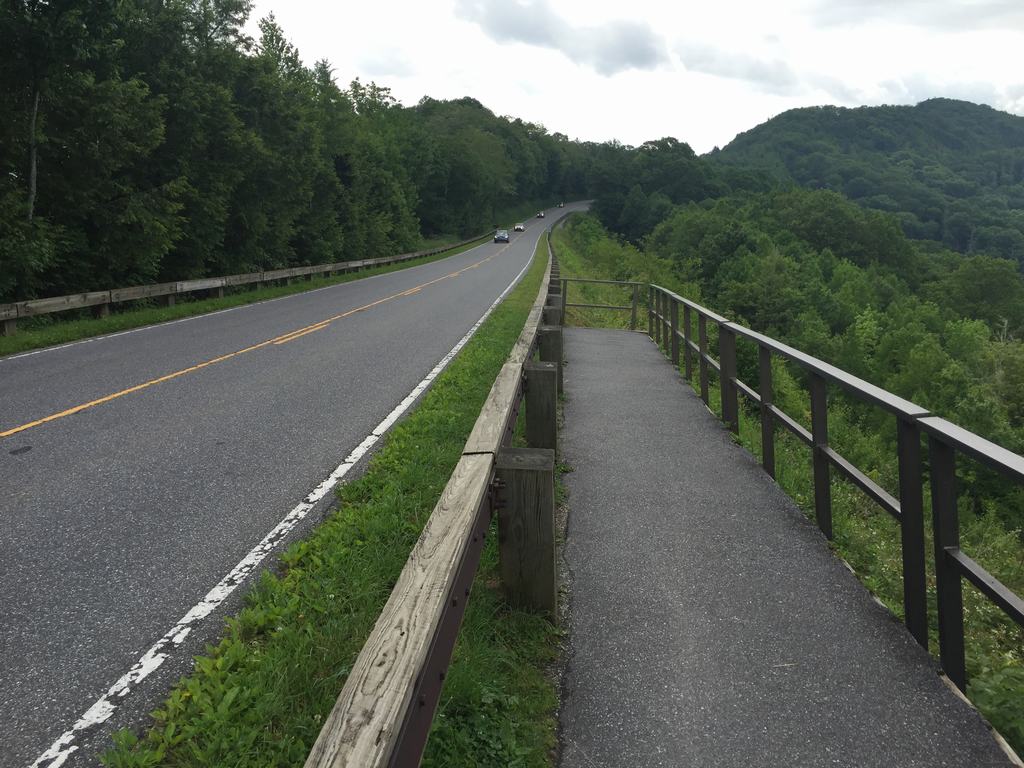 Silnice v Smoky Mountains s auty, vedle chodník se zábradlím a lesy