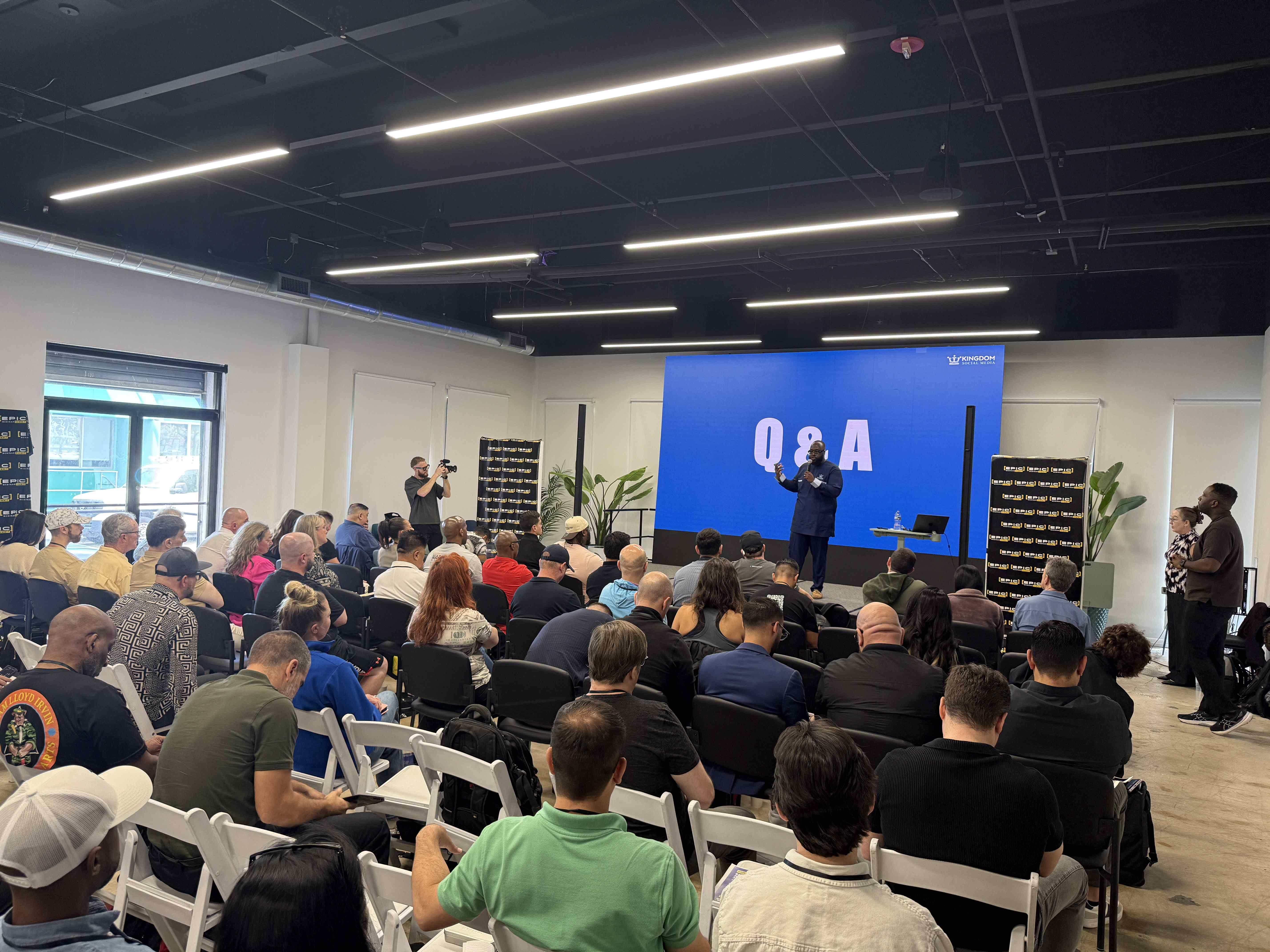Řečník před publikem, na velké obrazovce nápis Q&A a logo KINGDOM.