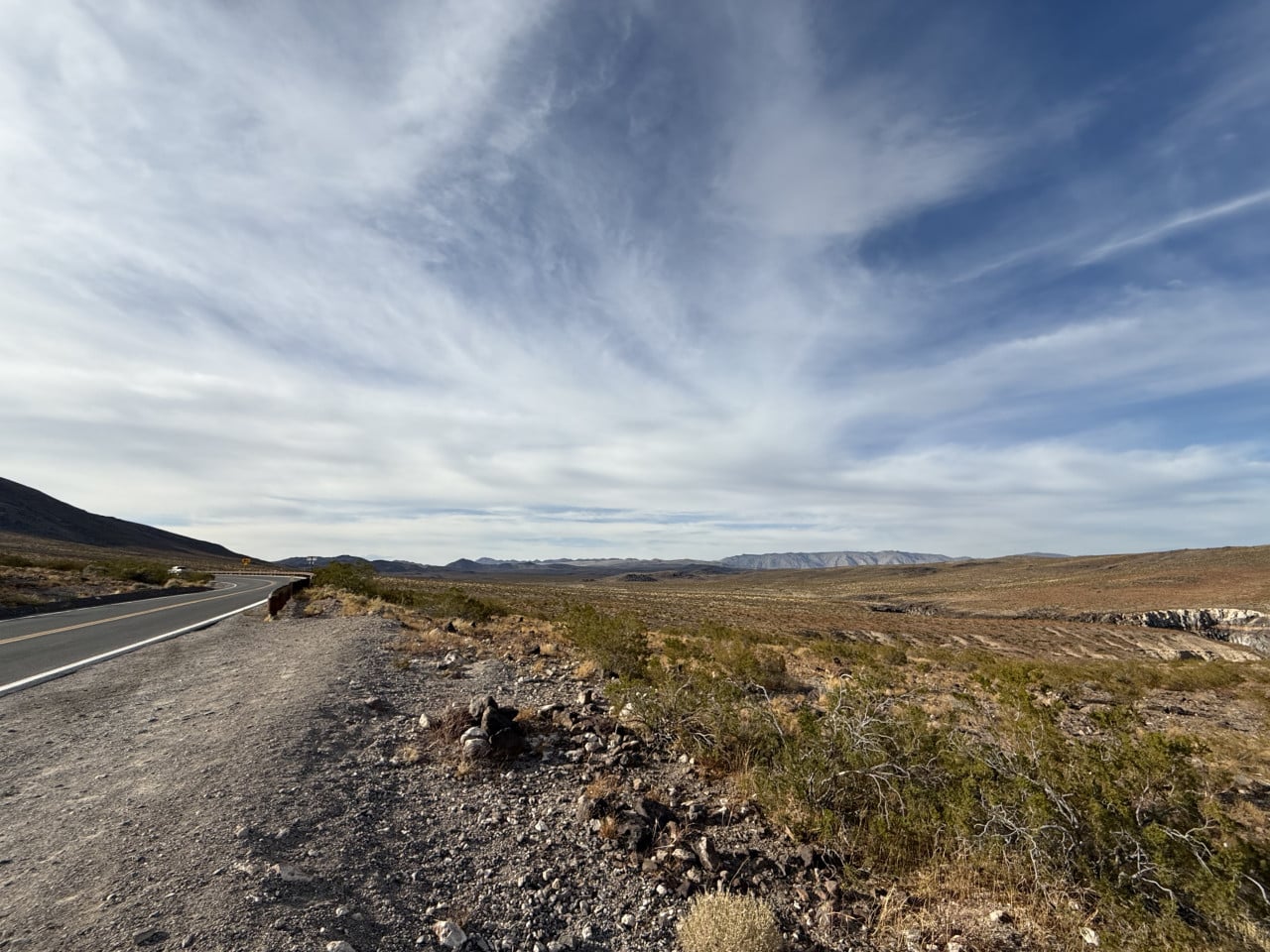 Silnice v Death Valley pod dramatickou oblohou a pouštní krajinou