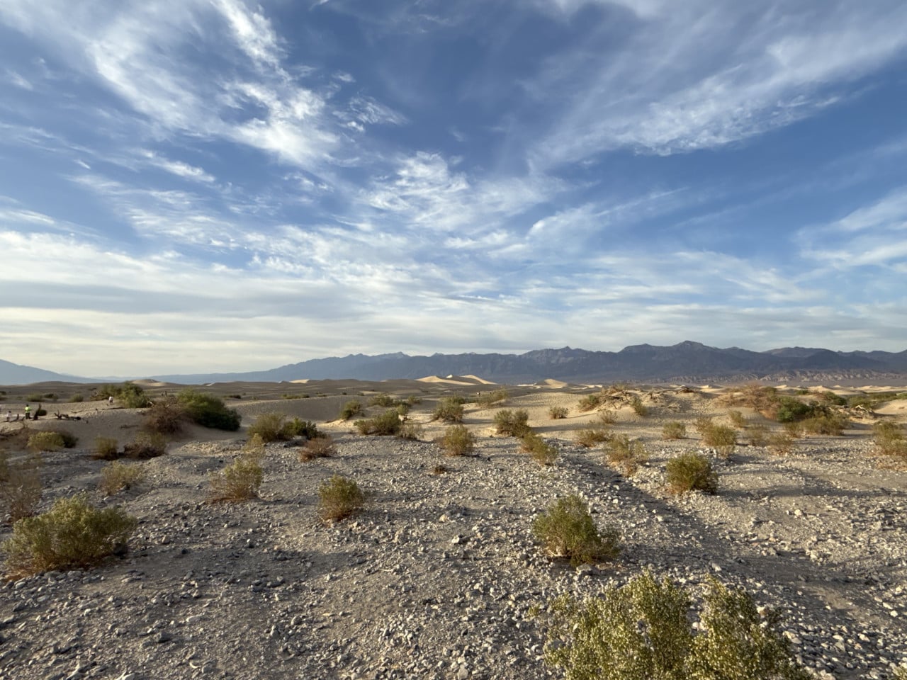 Pouštní duny v Death Valley pod rozlehlou modrou oblohou s mraky
