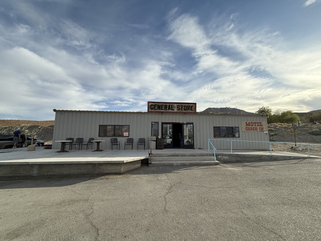 Pouštní motorest s nápisem GENERAL STORE a MOTEL CHECK-IN pod dramatickou oblohou