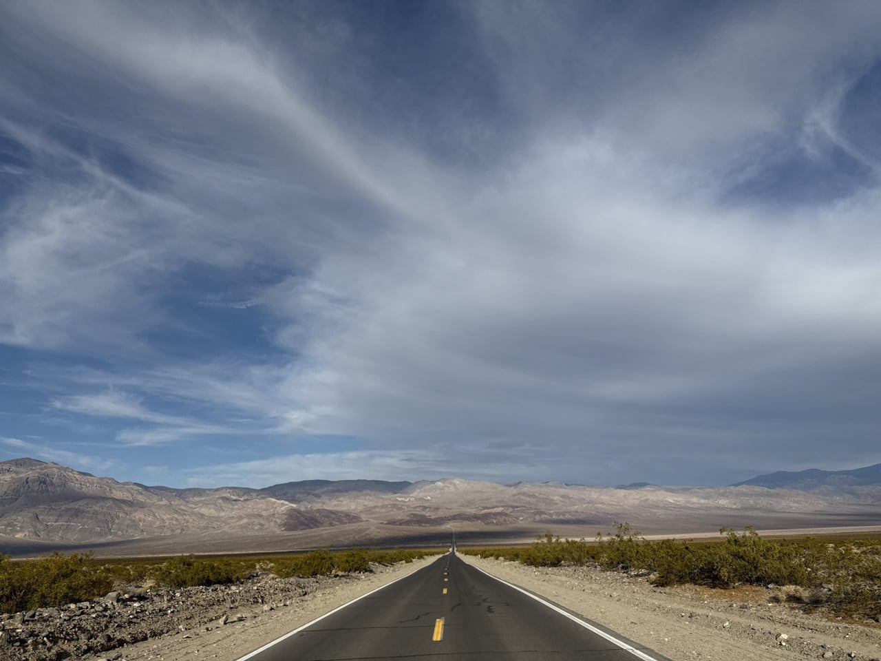 Silnice v Death Valley táhnoucí se k horám pod dramatickou oblohou