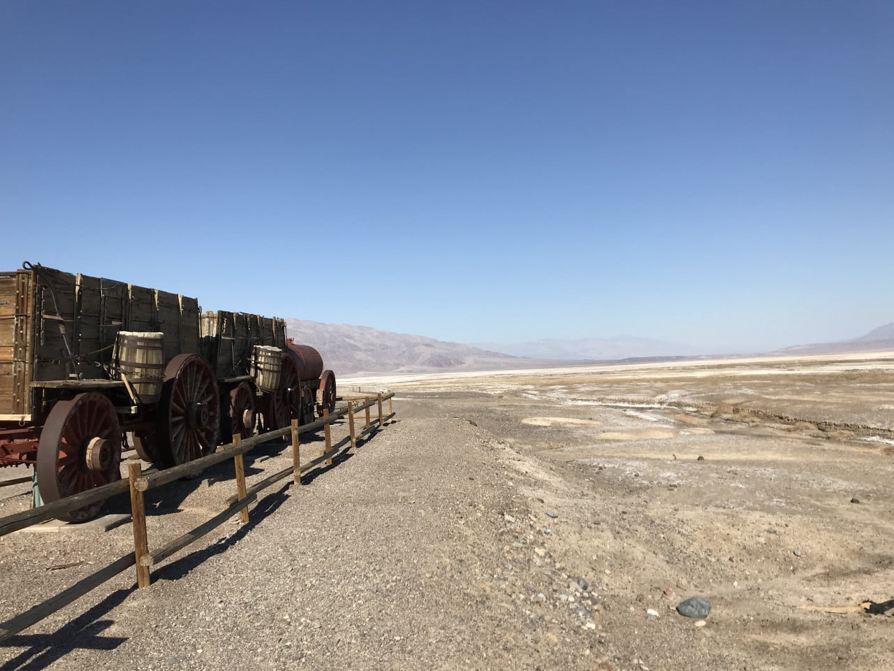 Staré vozíky v poušti Death Valley, širá rovina a modrá obloha