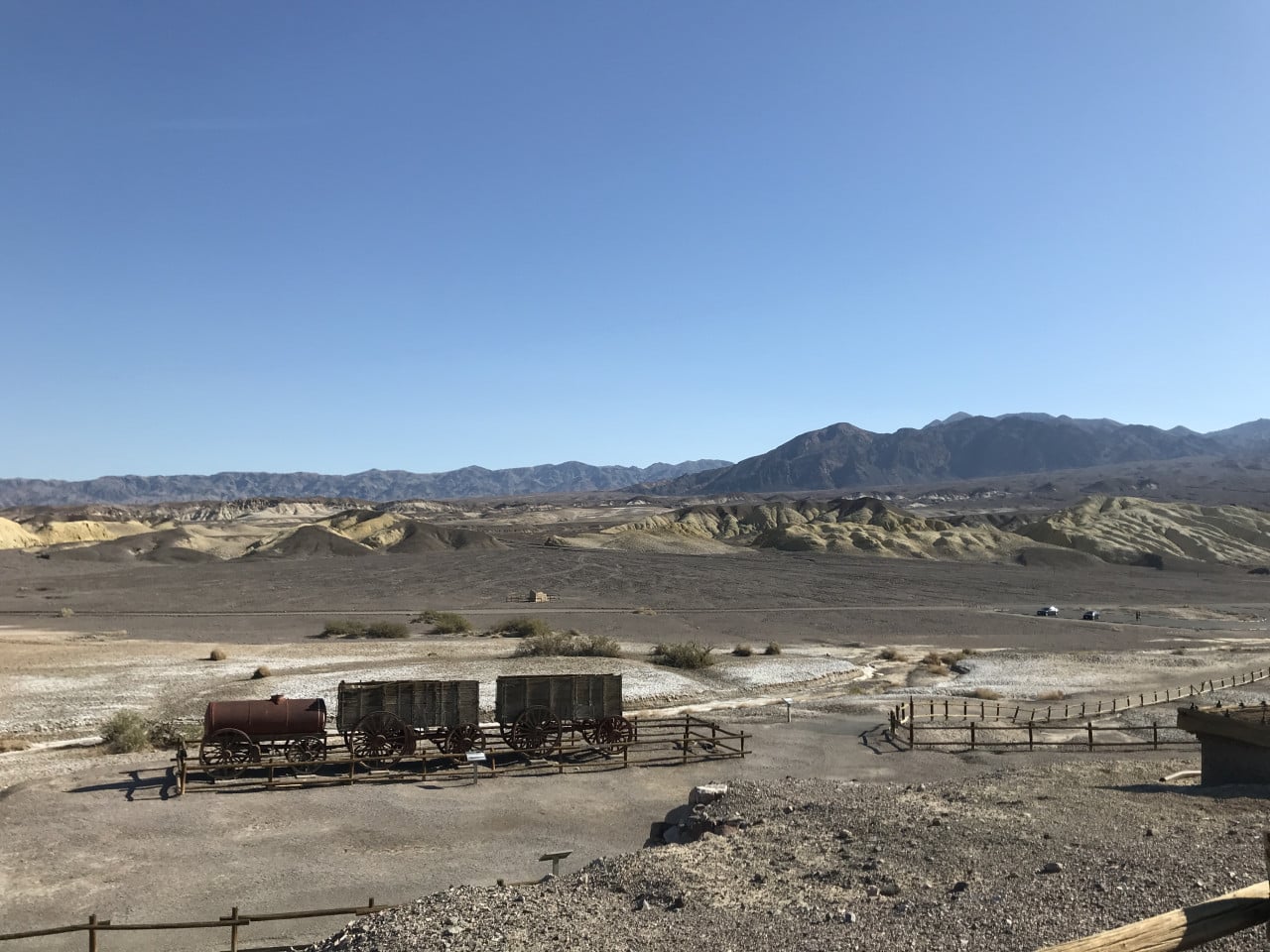 Pohled na suché údolí Death Valley s horami, vozíky a modrou oblohou