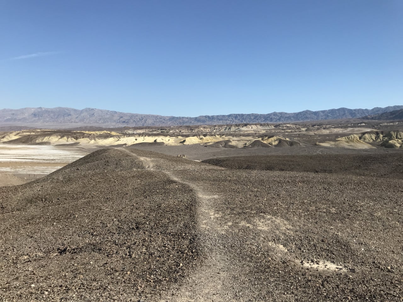 Pohled na barevné duny a hory v Death Valley pod modrou oblohou