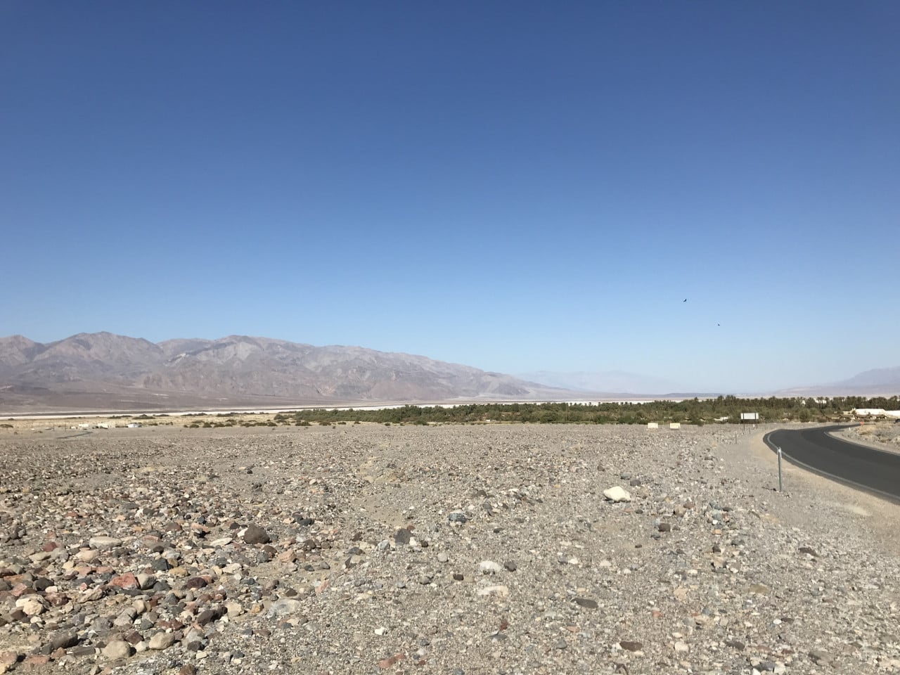 Pustá kamenitá krajina Death Valley s horami a klikatou silnicí.