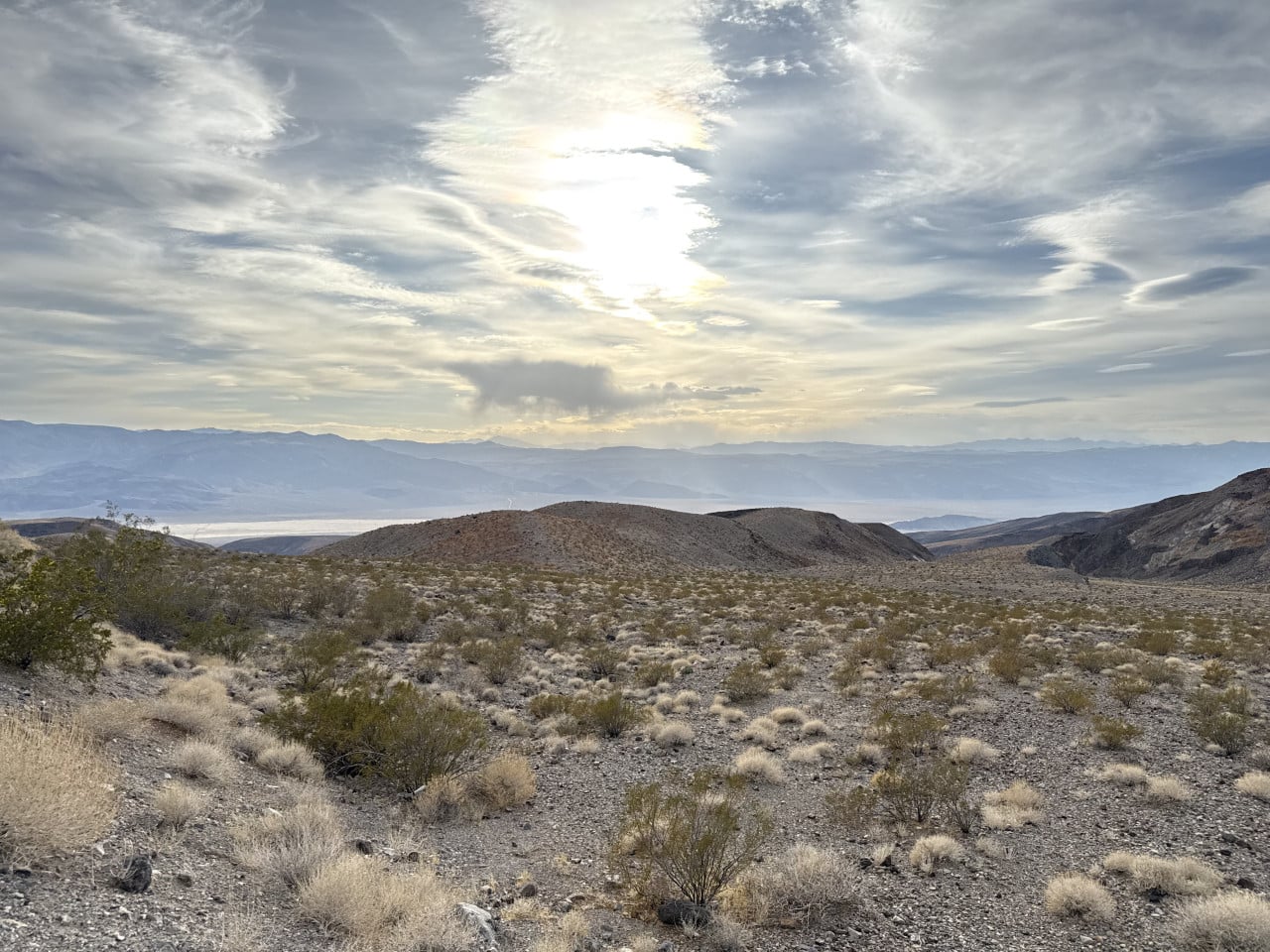 Pouštní krajina Death Valley s nízkými kopci a dramatickou oblohou