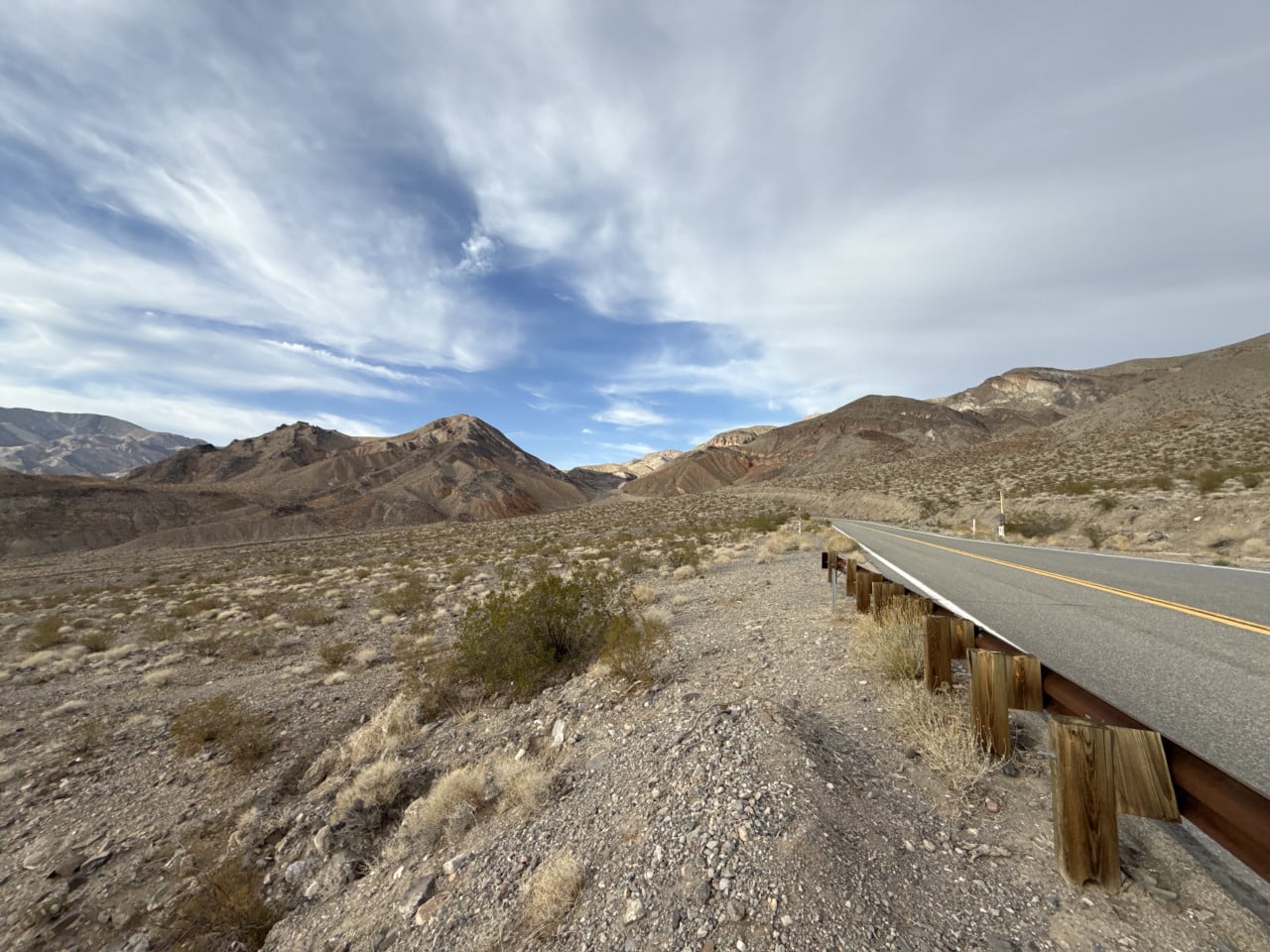 Pustá silnice v Death Valley mezi skalnatými horami a dramatickými mraky