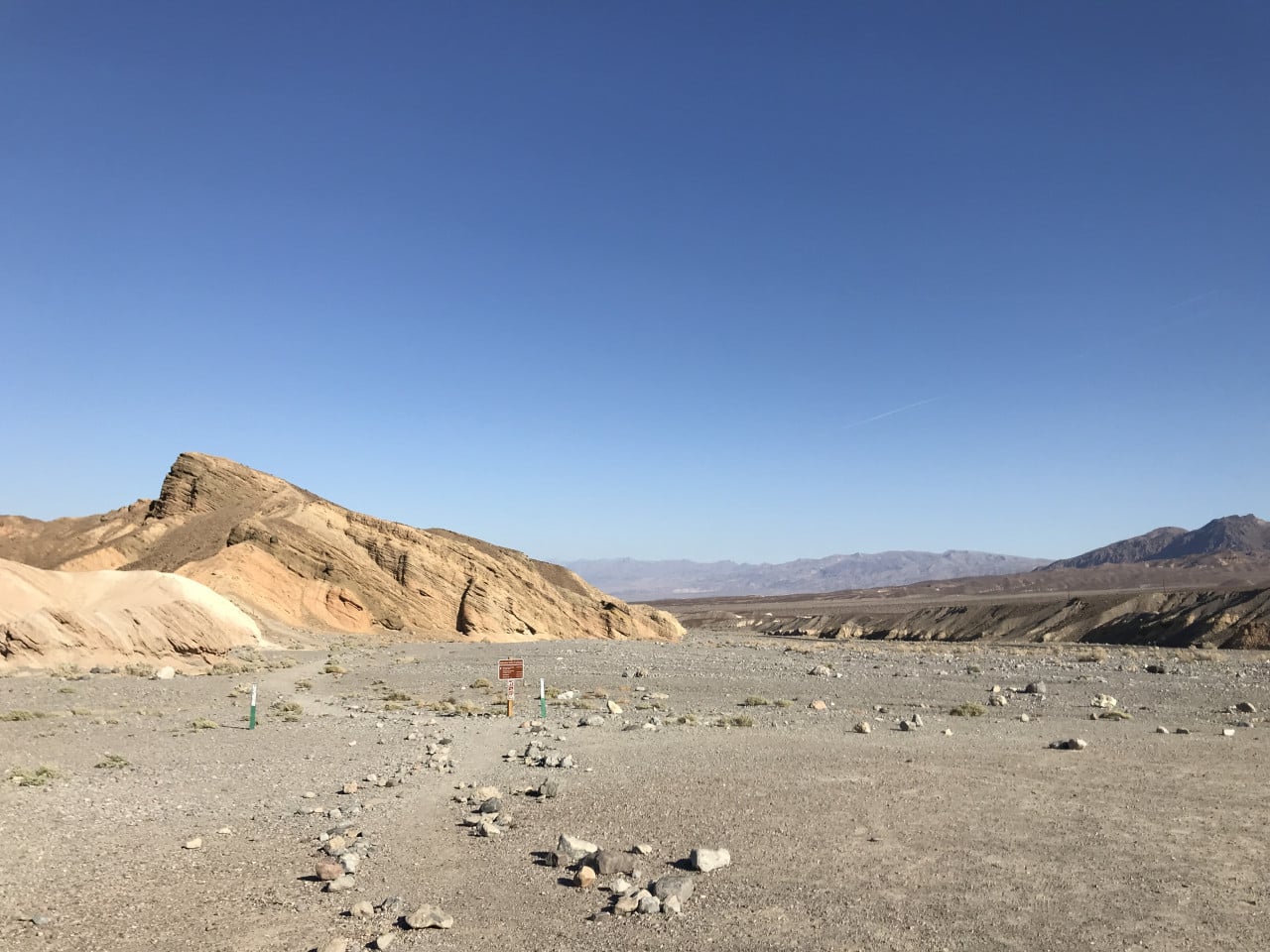 Suché údolí v Death Valley s barevnými skalami a modrou oblohou
