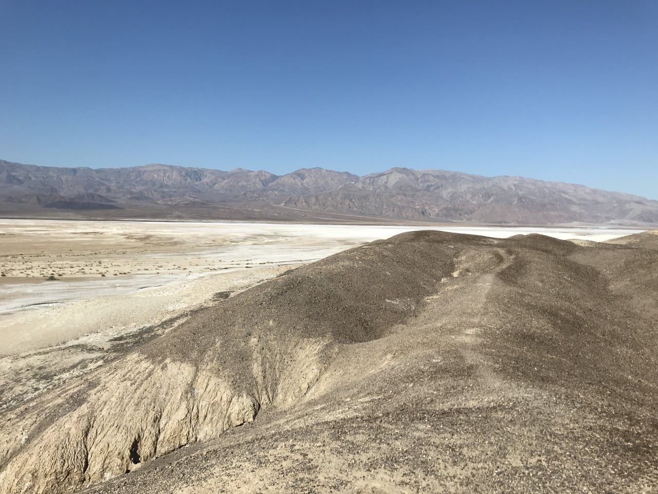 Pouštní krajina Death Valley s bílou solnou plání a horami v dálce