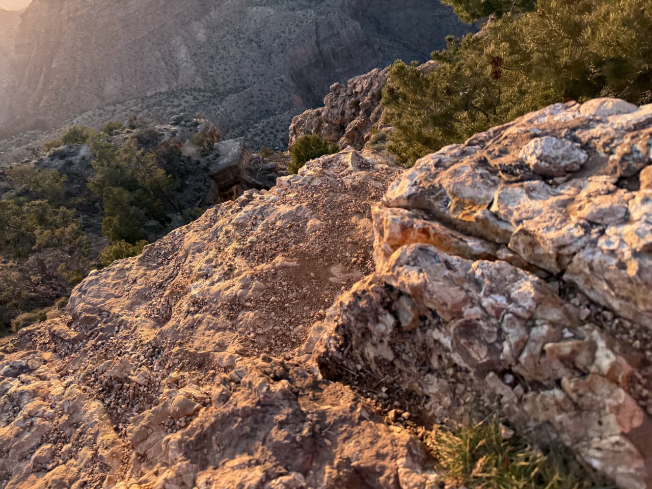 Zlatě osvětlená skalnatá hrana Grand Canyonu s výhledem do hluboké propasti.