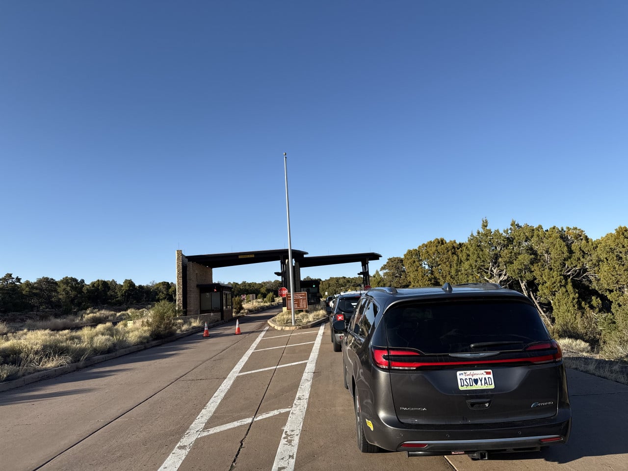 Vozidlo na parkovišti u vstupu Desert View Point v Grand Canyonu s moderní budovou a pouštní vegetací.