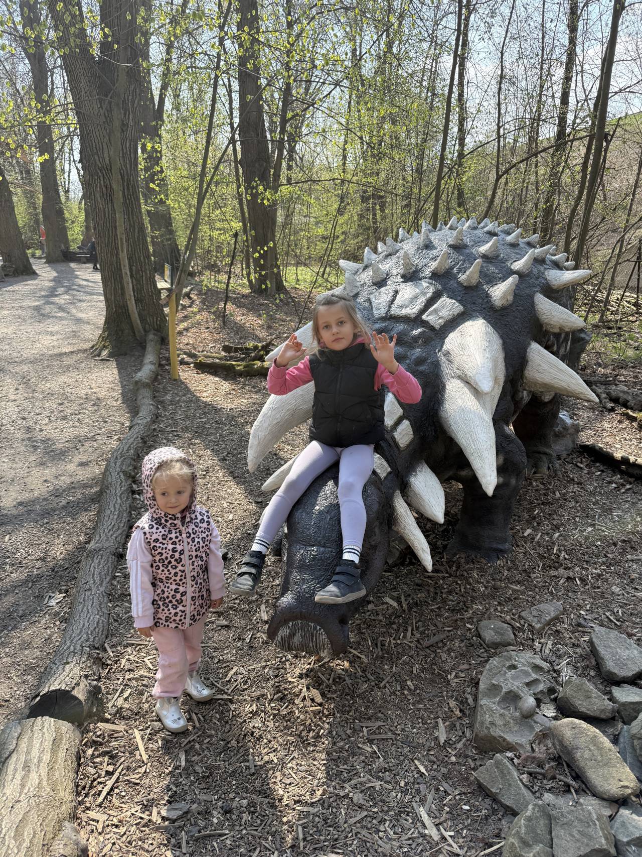 Dvě děti u modelu ostnitého dinosaura v lese v DinoParku Vyškov