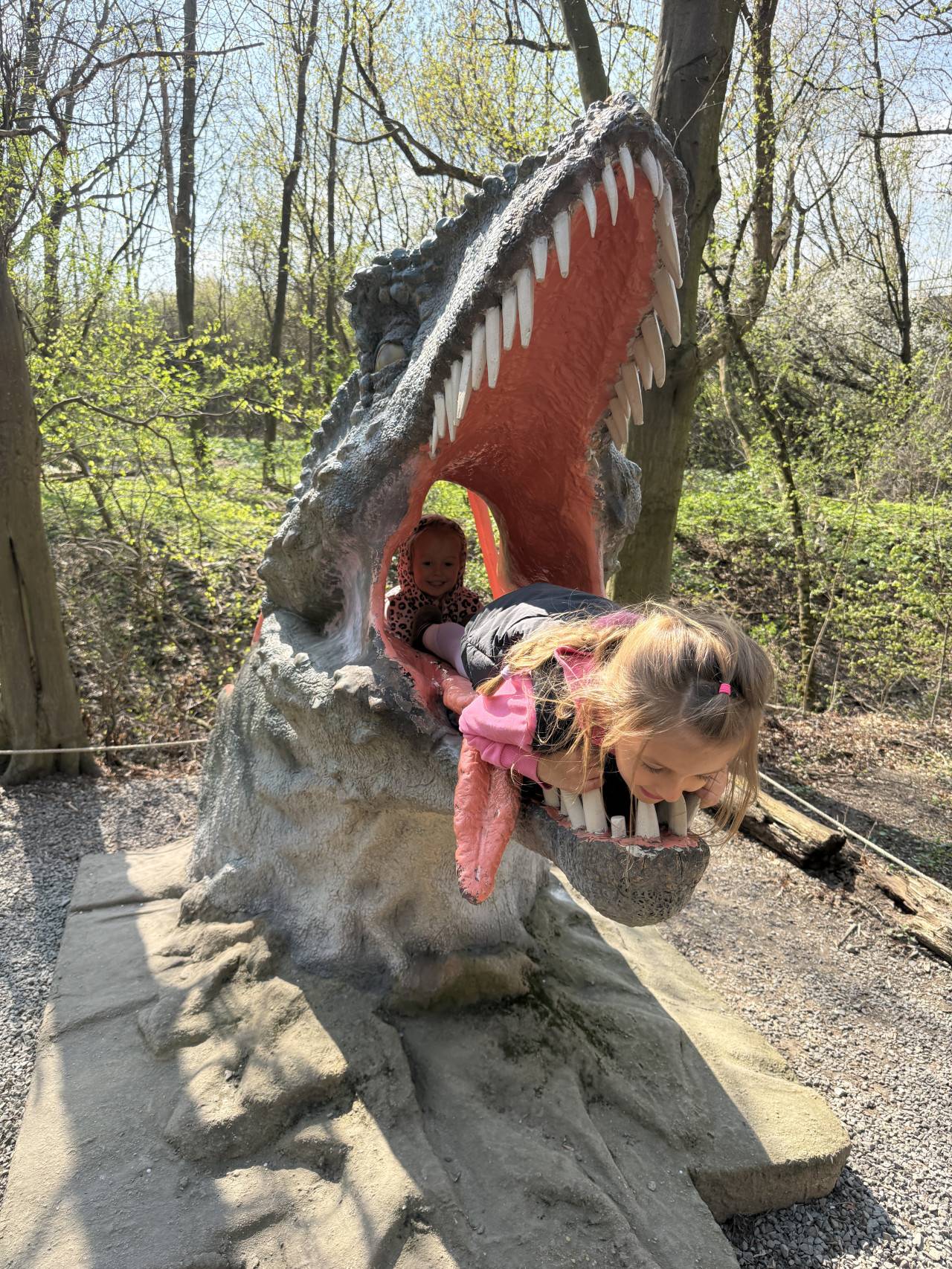 Děti si hrají v tlamě dinosauří sochy v lesoparku DinoPark Vyškov