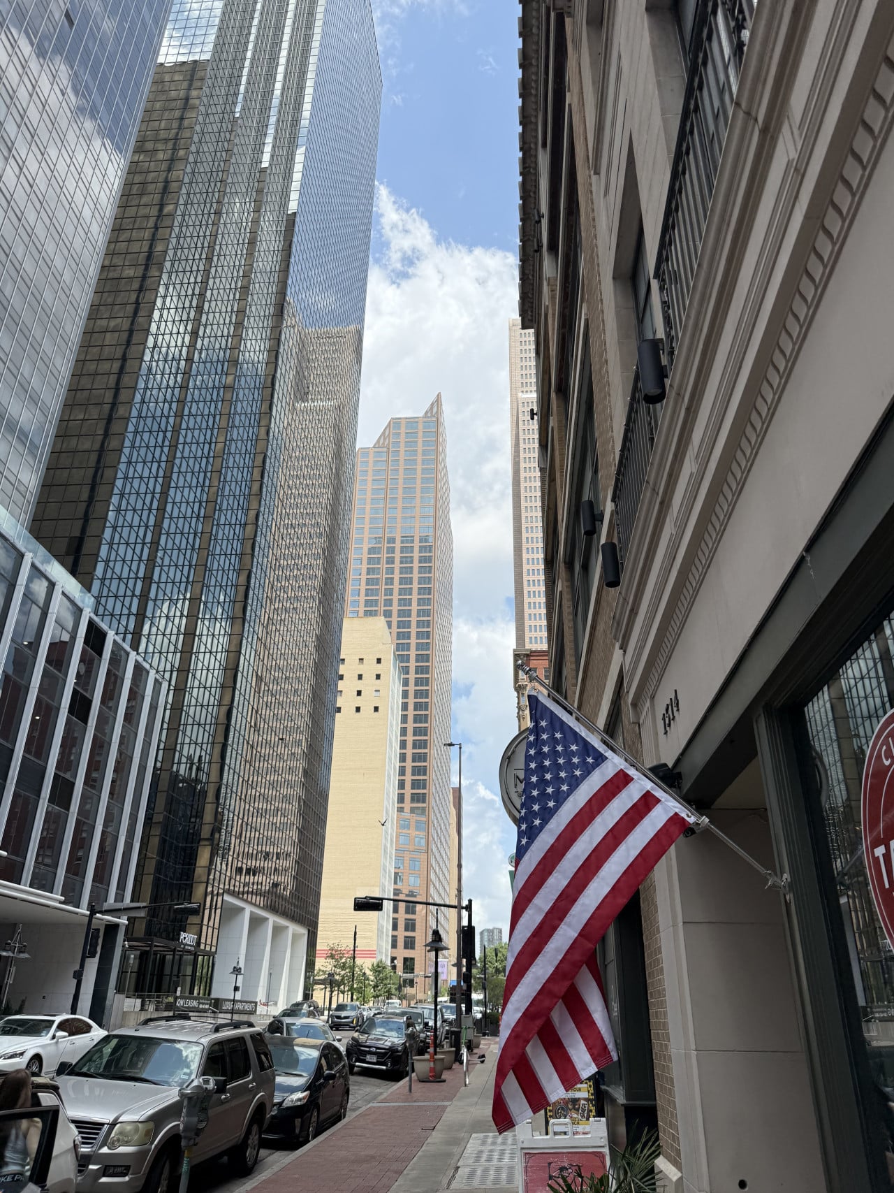 Ulice v downtown Dallasu, mrakodrapy, zaparkovaná auta a americká vlajka u 1414.