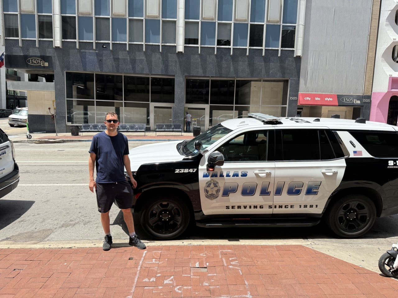 Muž u policejního SUV DALLAS POLICE, SERVING SINCE 1881, 1505 Elm.