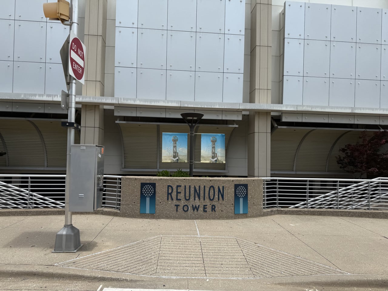 Cedule REUNION TOWER před budovou, vlevo dopravní značka DO NOT ENTER.