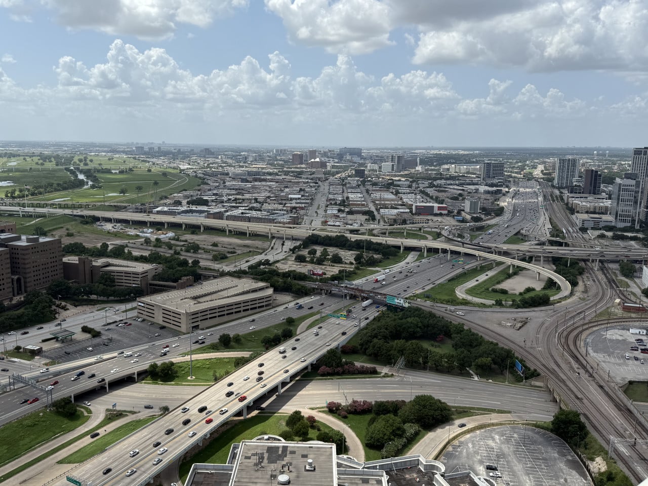 Pohled z výšky na dálniční křižovatku s provozem a panoramatem Dallasu