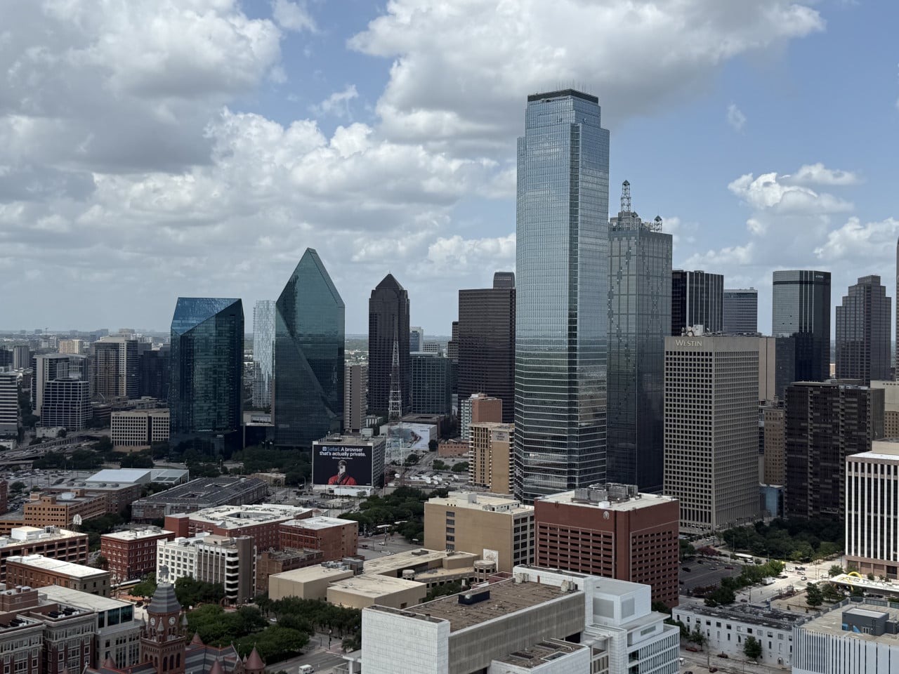 Panorama downtown Dallas s mrakodrapy, obloha s mraky, budova Westin, nižší domy.