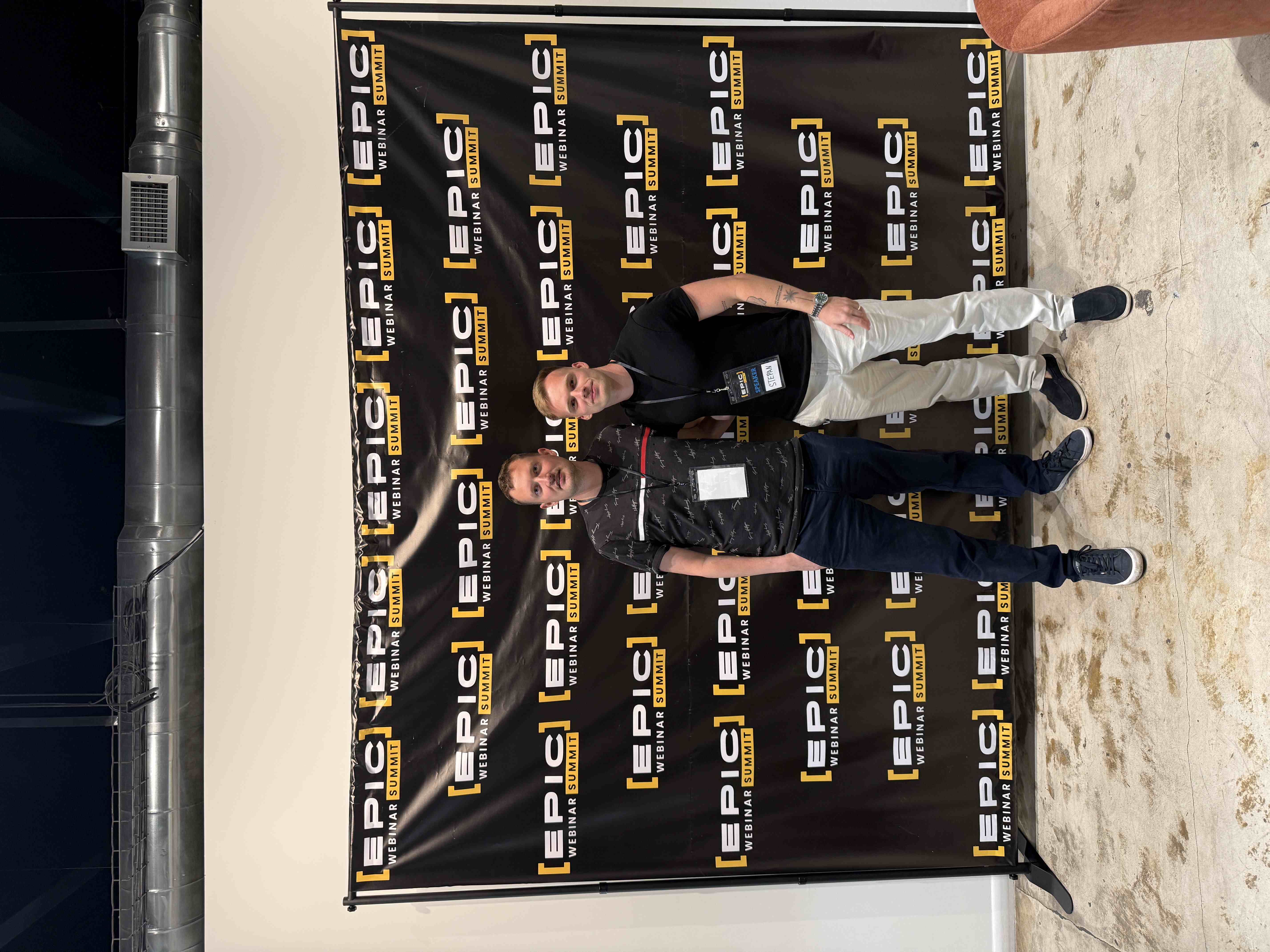 Dva muži Ondřej Barták a Štěpán Hlinka s visačkami před fotostěnou [EPIC] WEBINAR SUMMIT, badge SPEAKER STEPAN