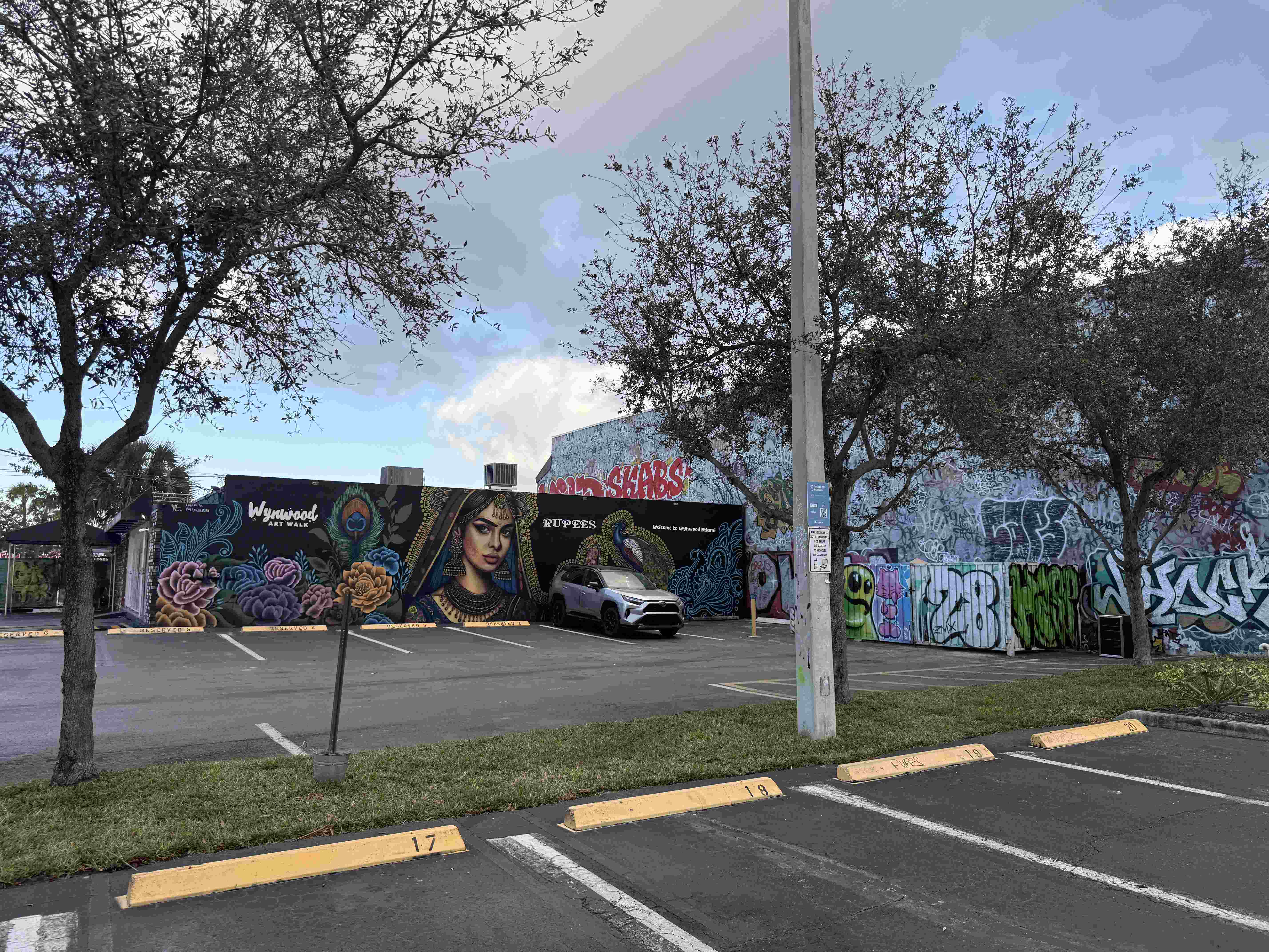 Parkoviště u murálu Wynwood Art Walk, nápis RUPEES, auto a graffiti